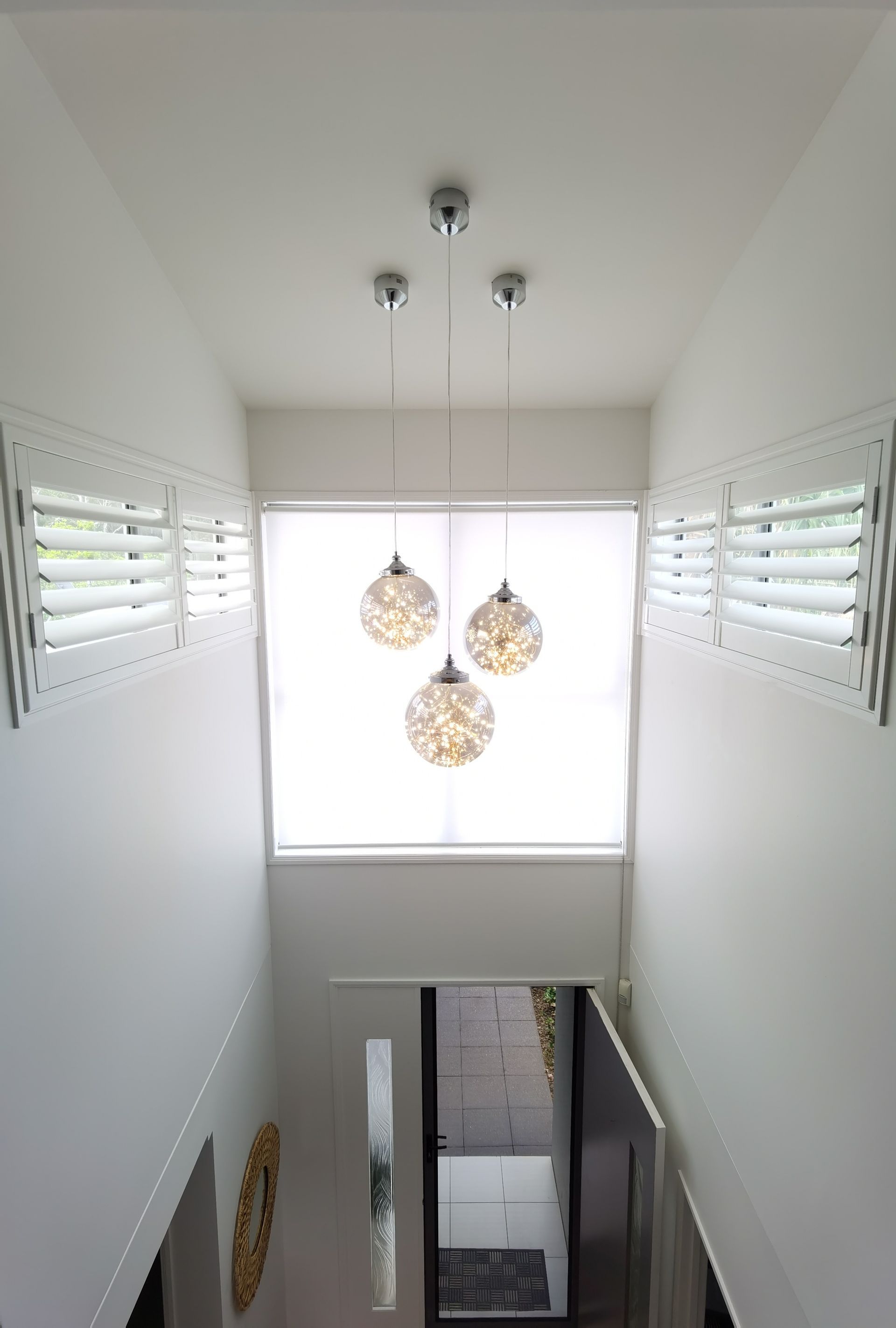 A staircase with a window and a chandelier hanging from the ceiling.