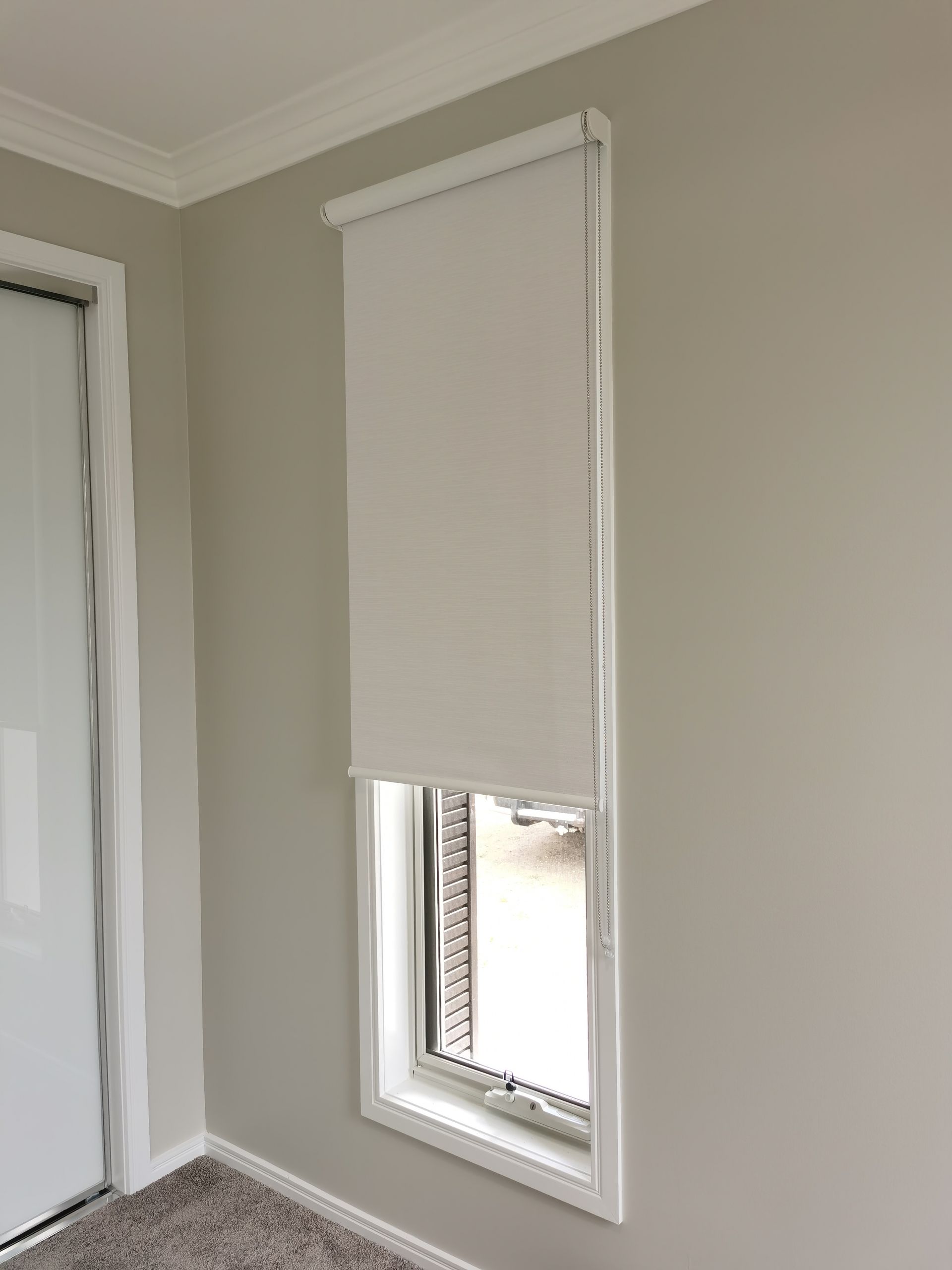 A room with a window and a white blind on it.