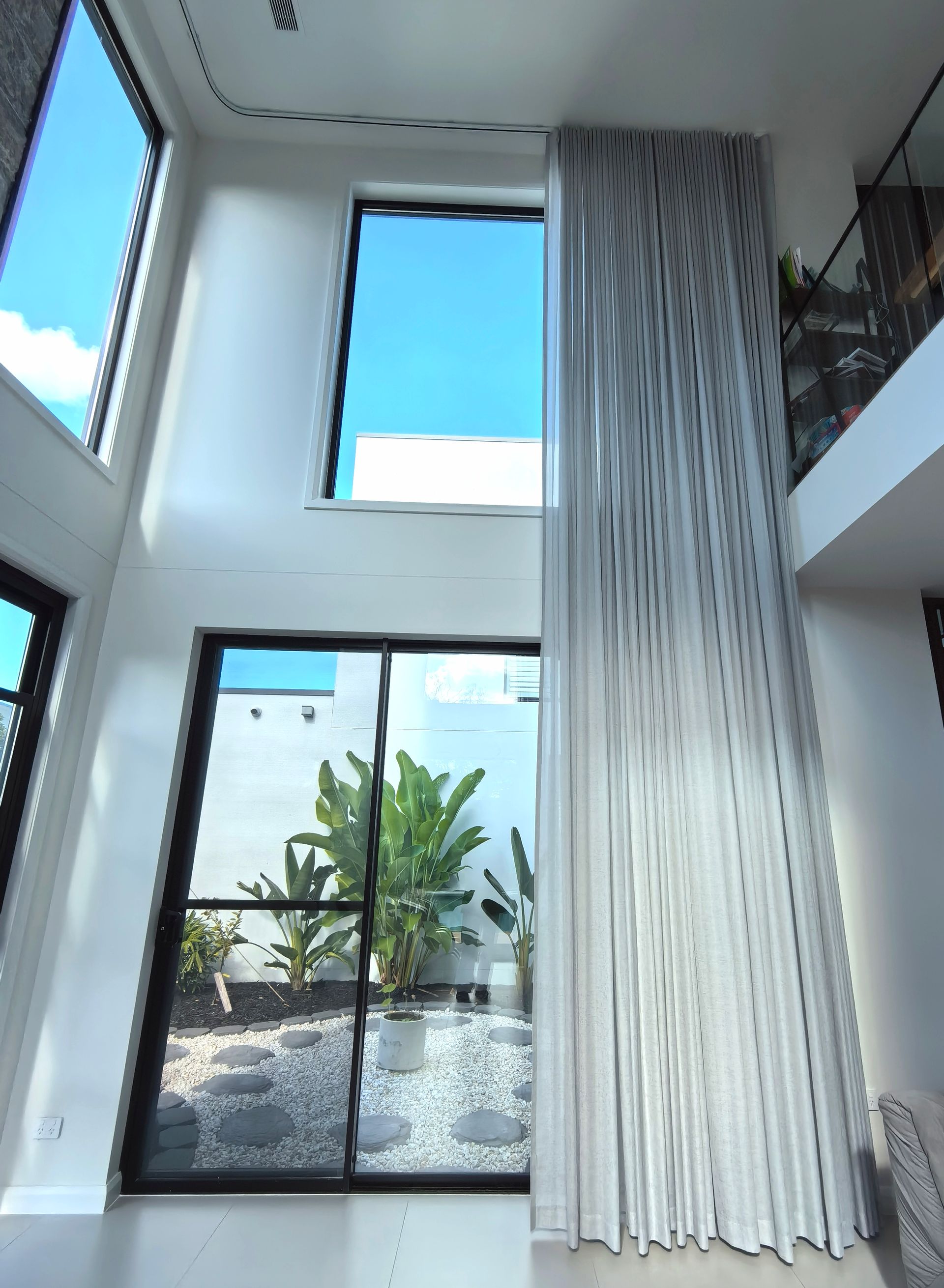 A room with a lot of windows and curtains hanging from the ceiling.