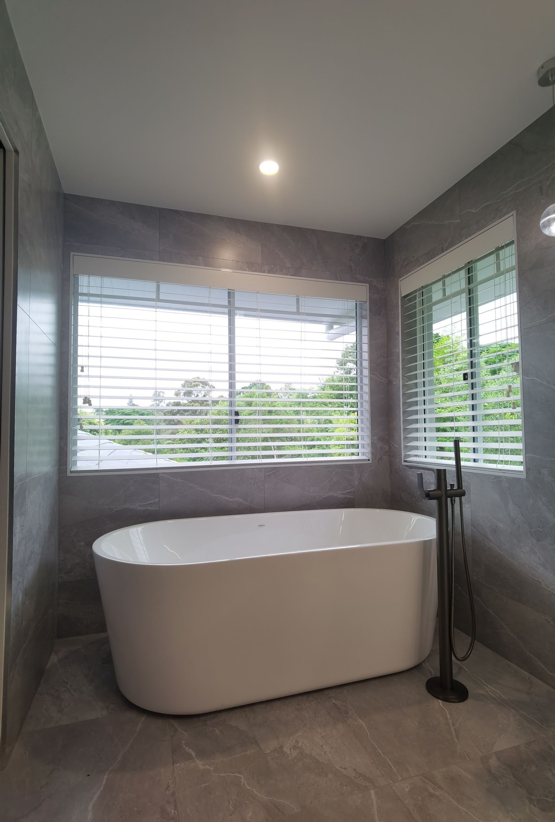 A bathroom with a bathtub and two windows.