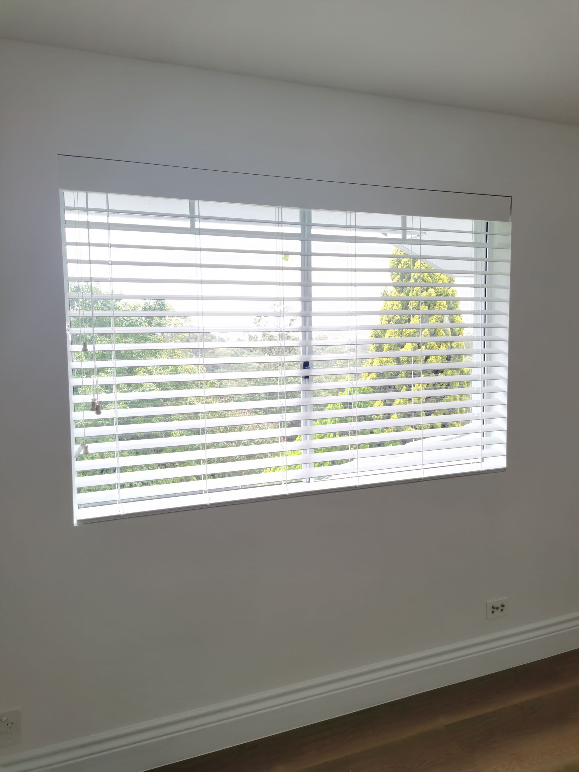 A large window with blinds on it in an empty room.