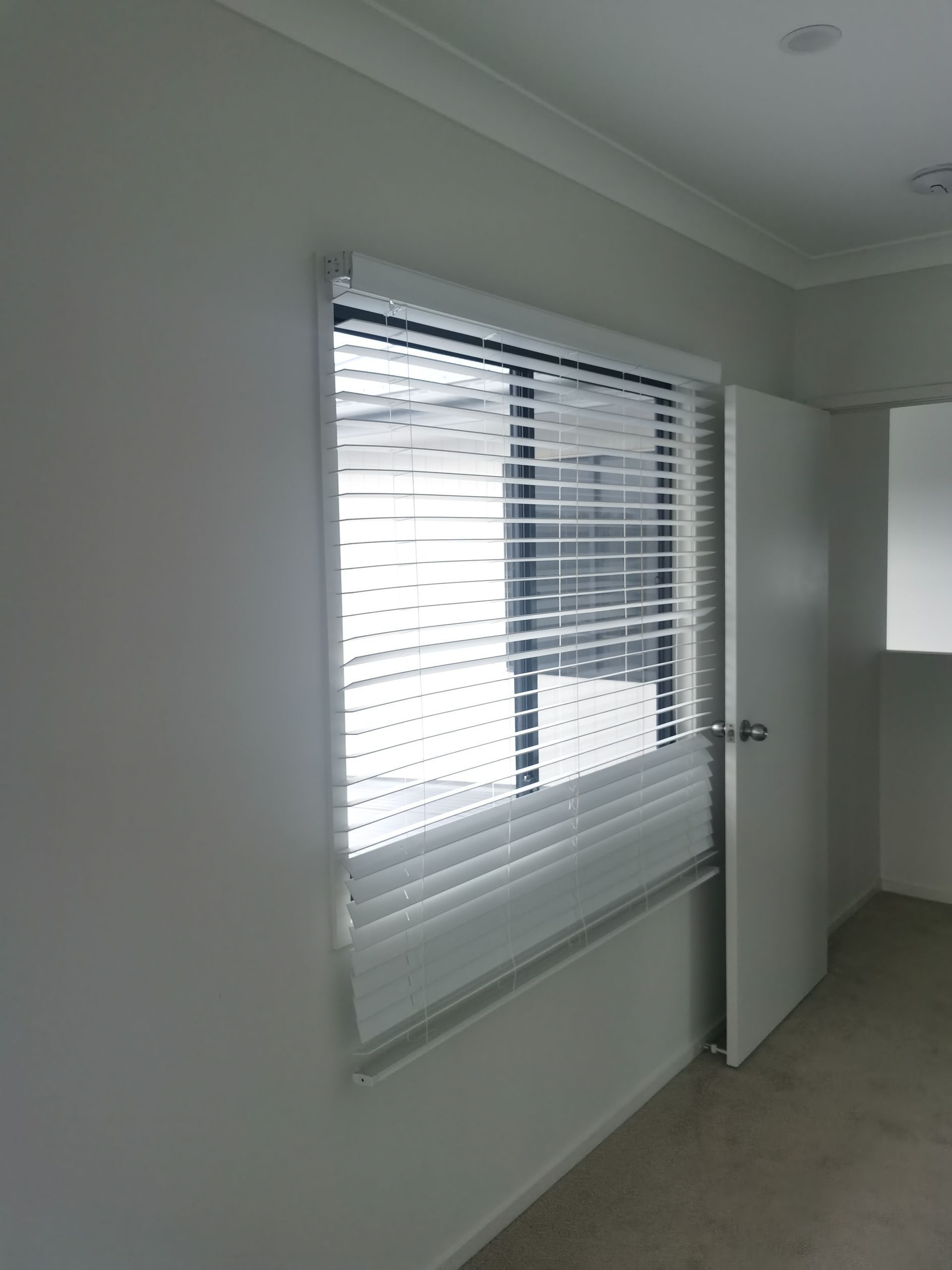 An empty room with a window with blinds and a door