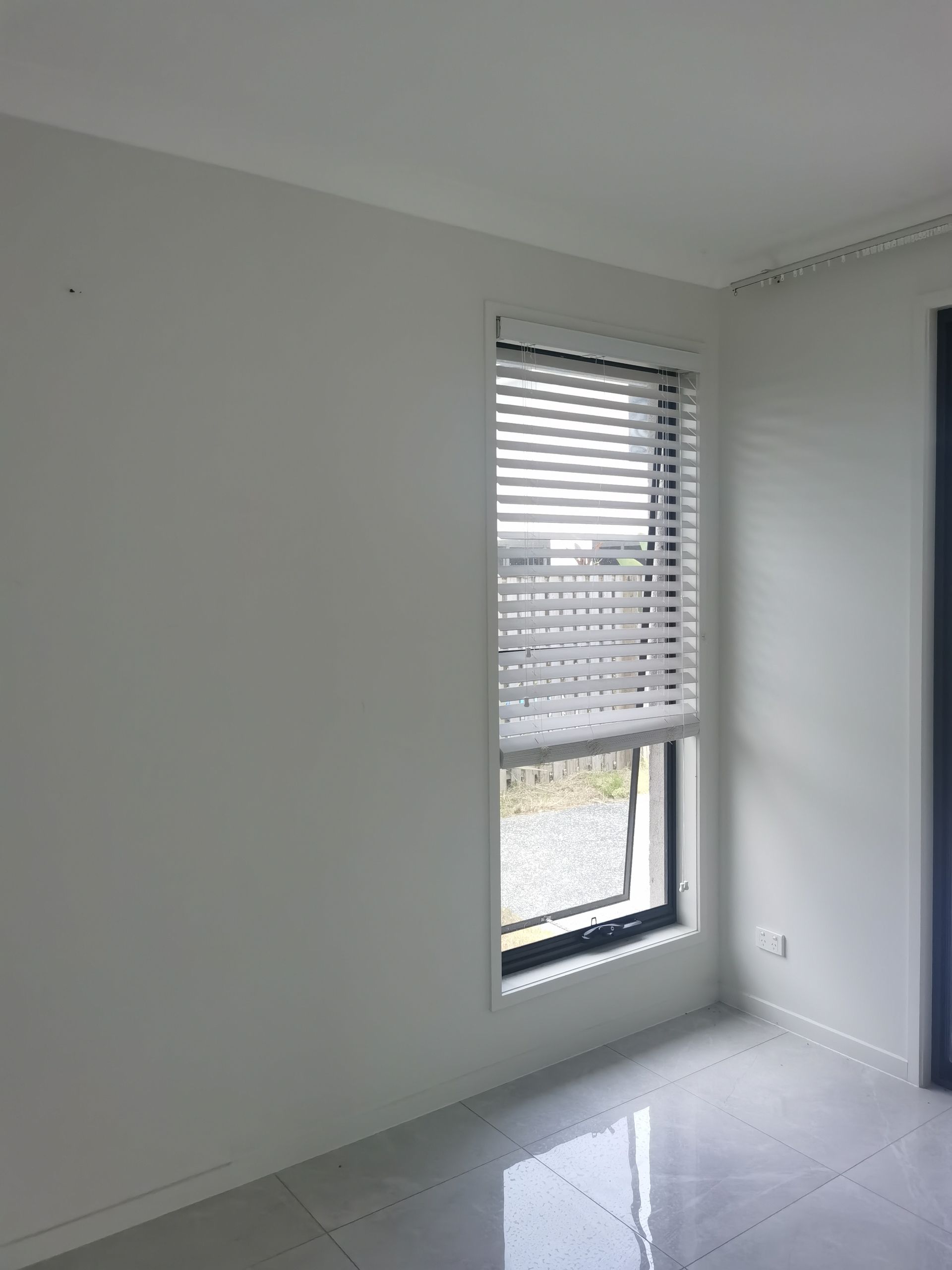 An empty room with a window and blinds on it.