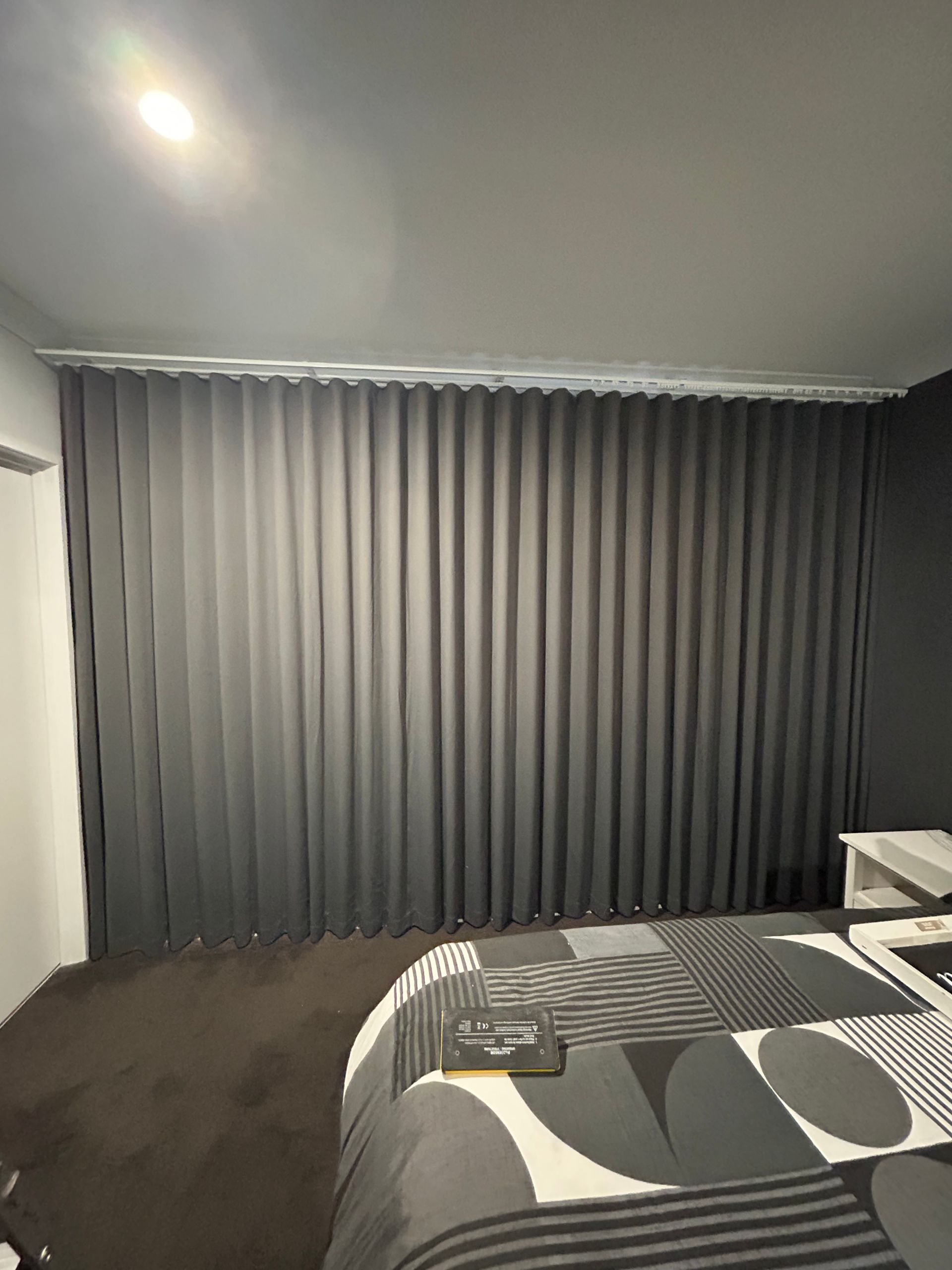 A bedroom with a bed , nightstand , and curtains.