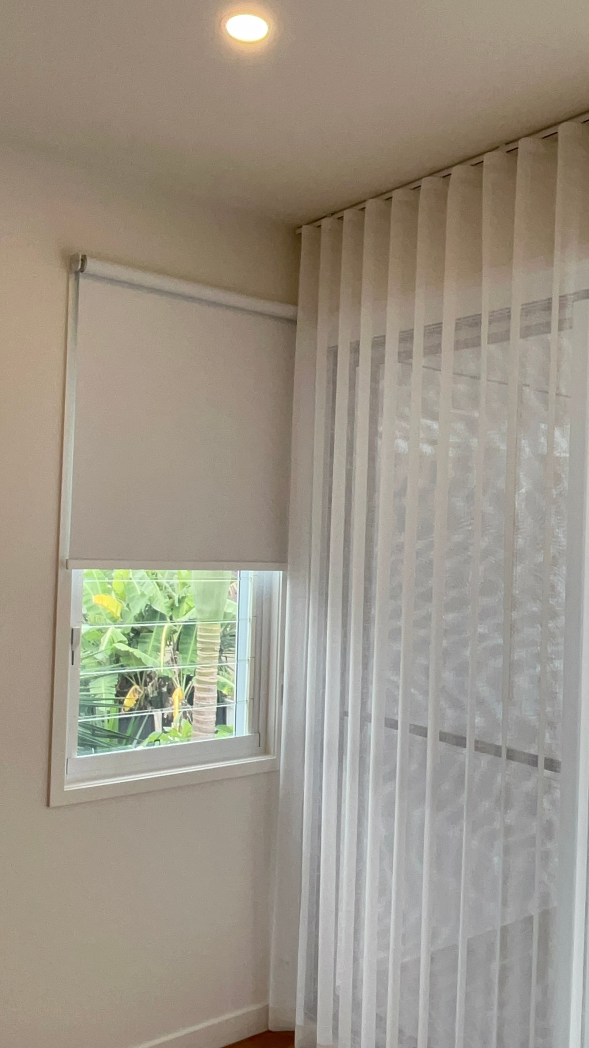 A bedroom with a window and white curtains.