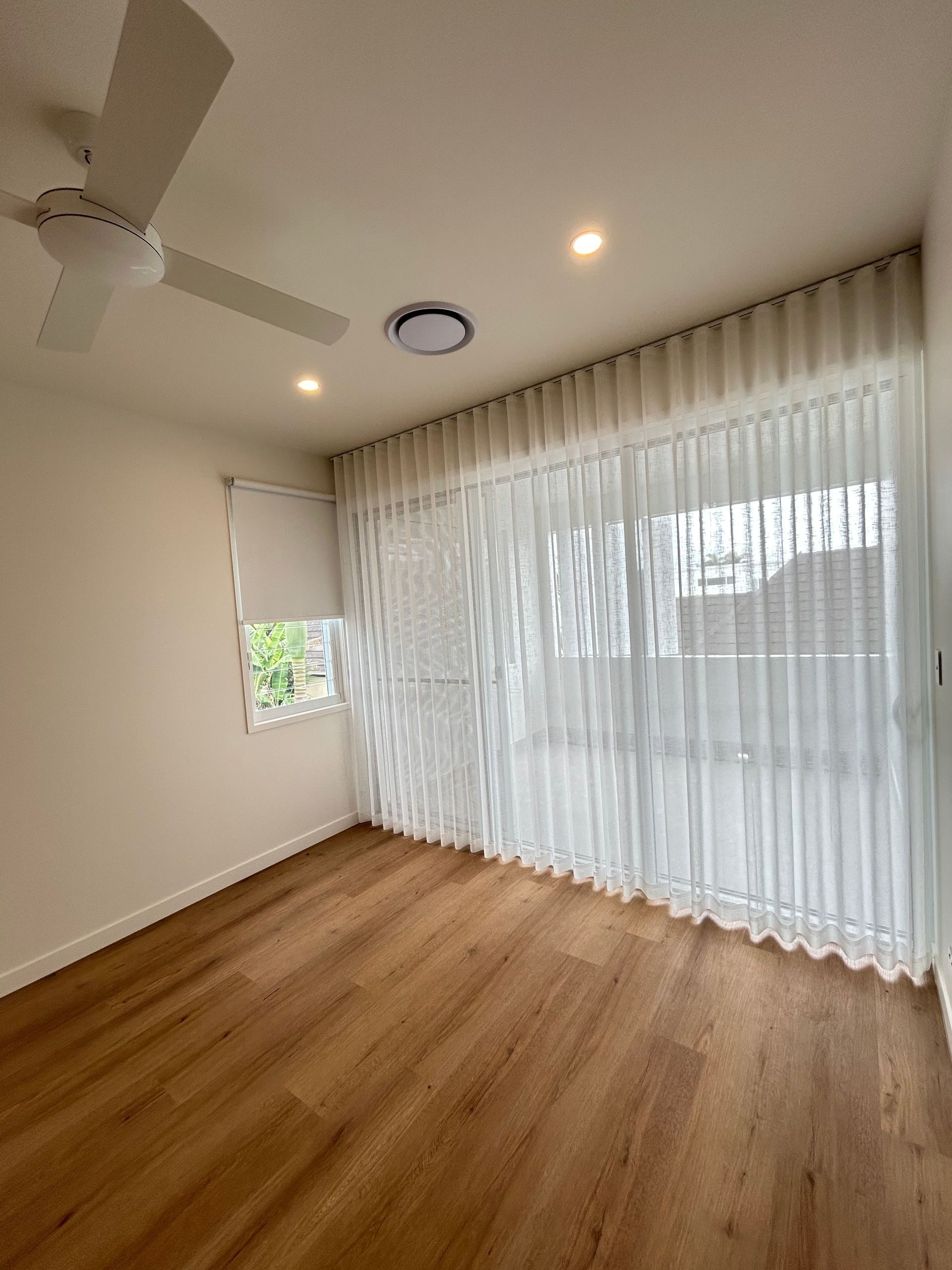 There is a ceiling fan in the room and a large window.