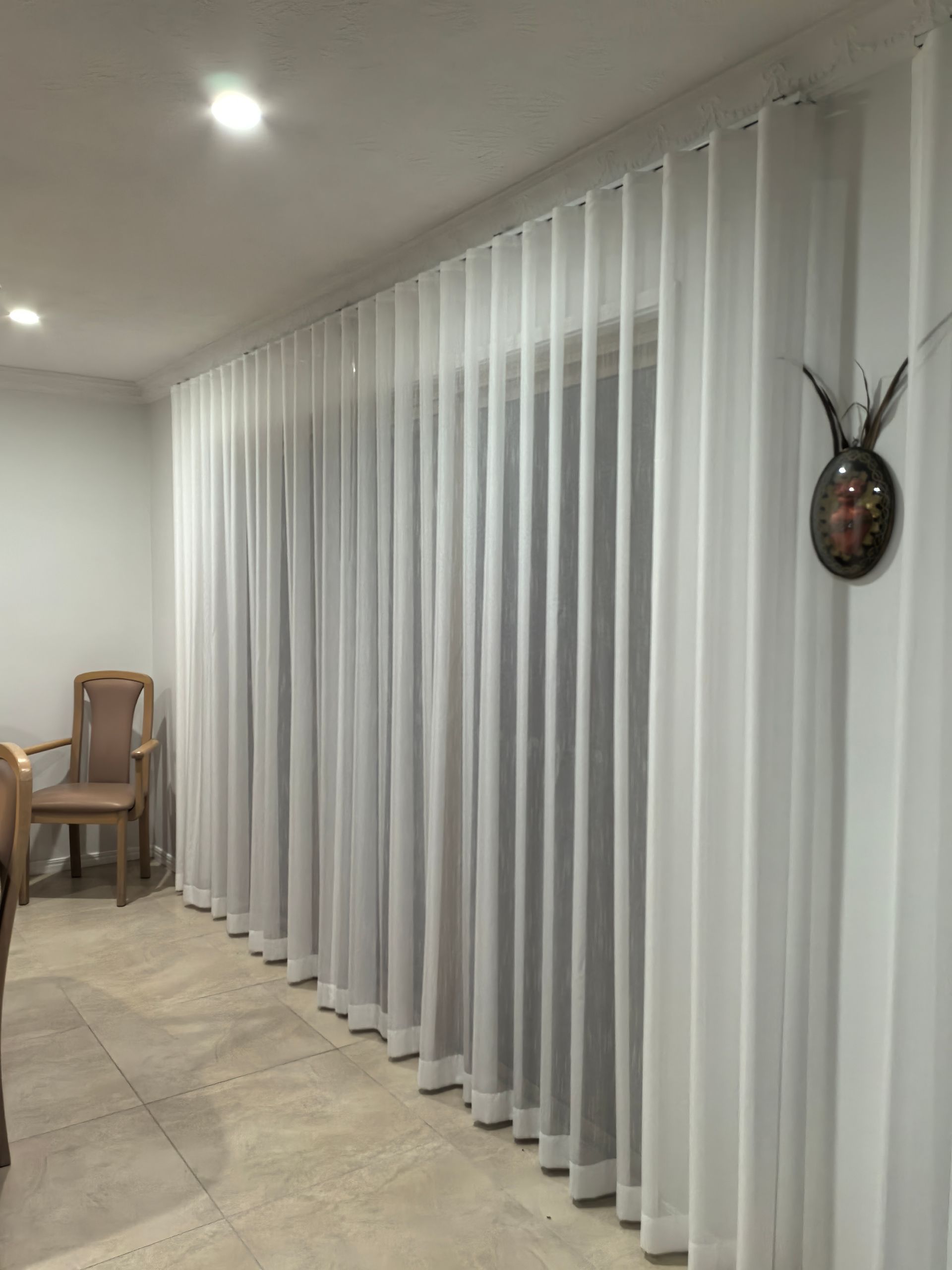 A living room with white curtains and a chair.