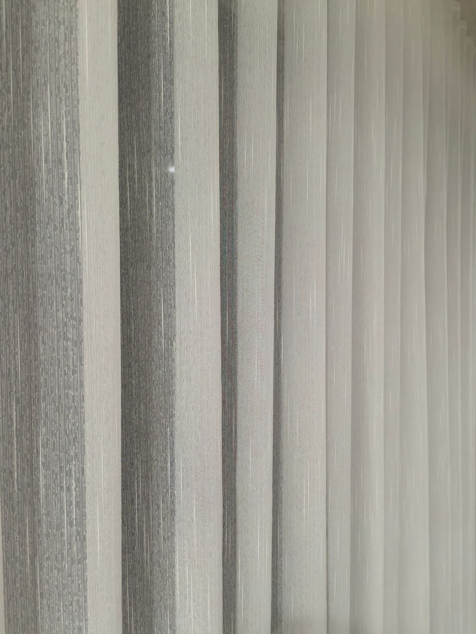 A close up of a row of vertical blinds on a window.