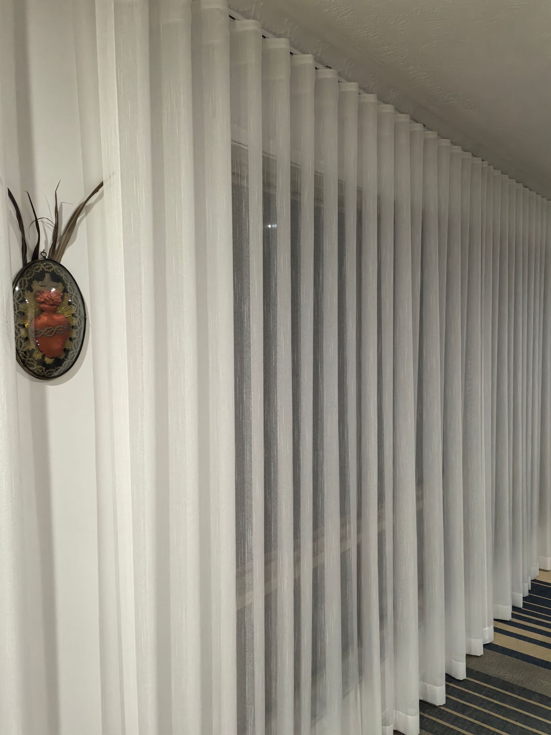 A row of white curtains are hanging on a wall in a room.