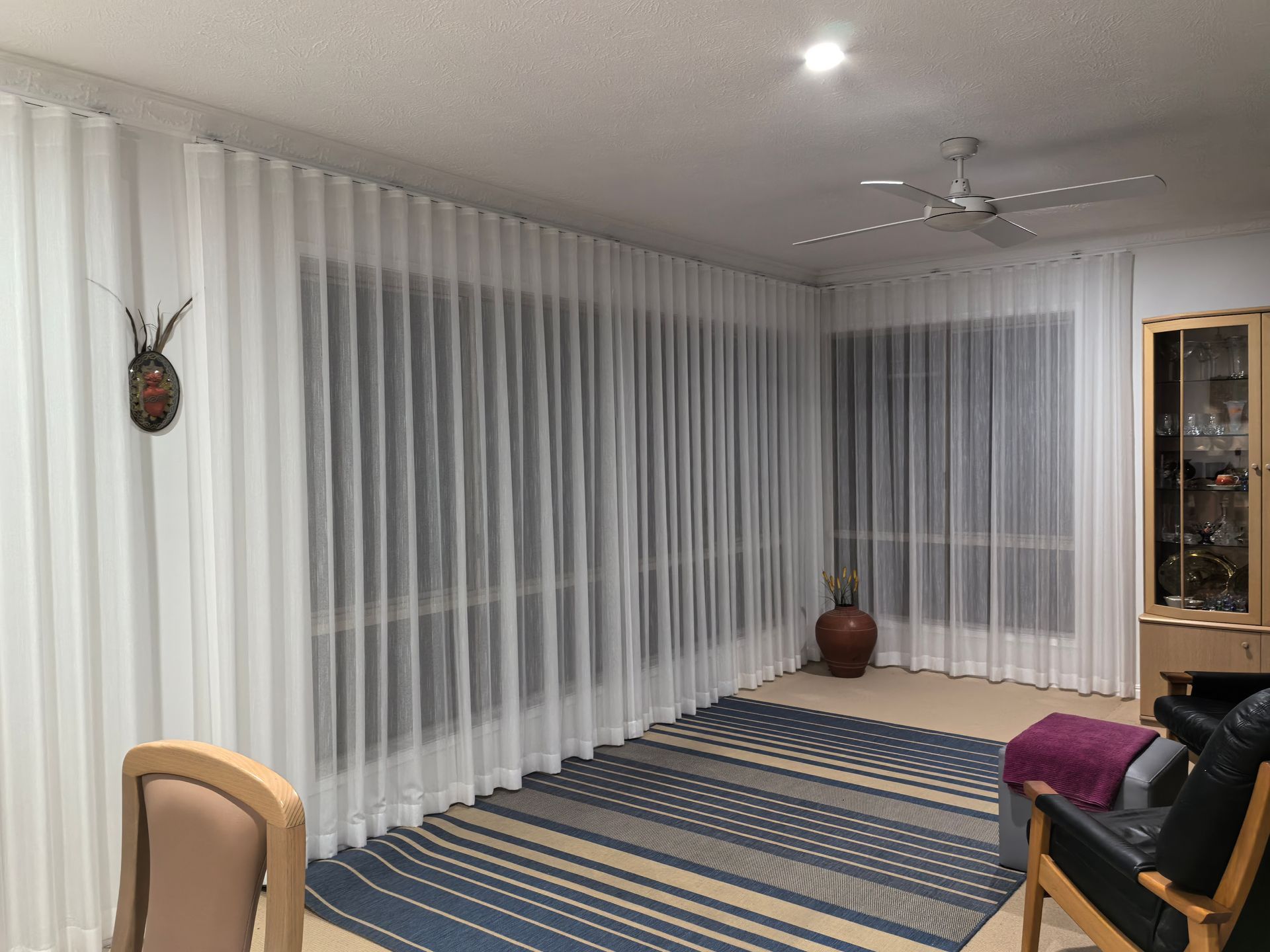 A living room with white curtains and a rug.