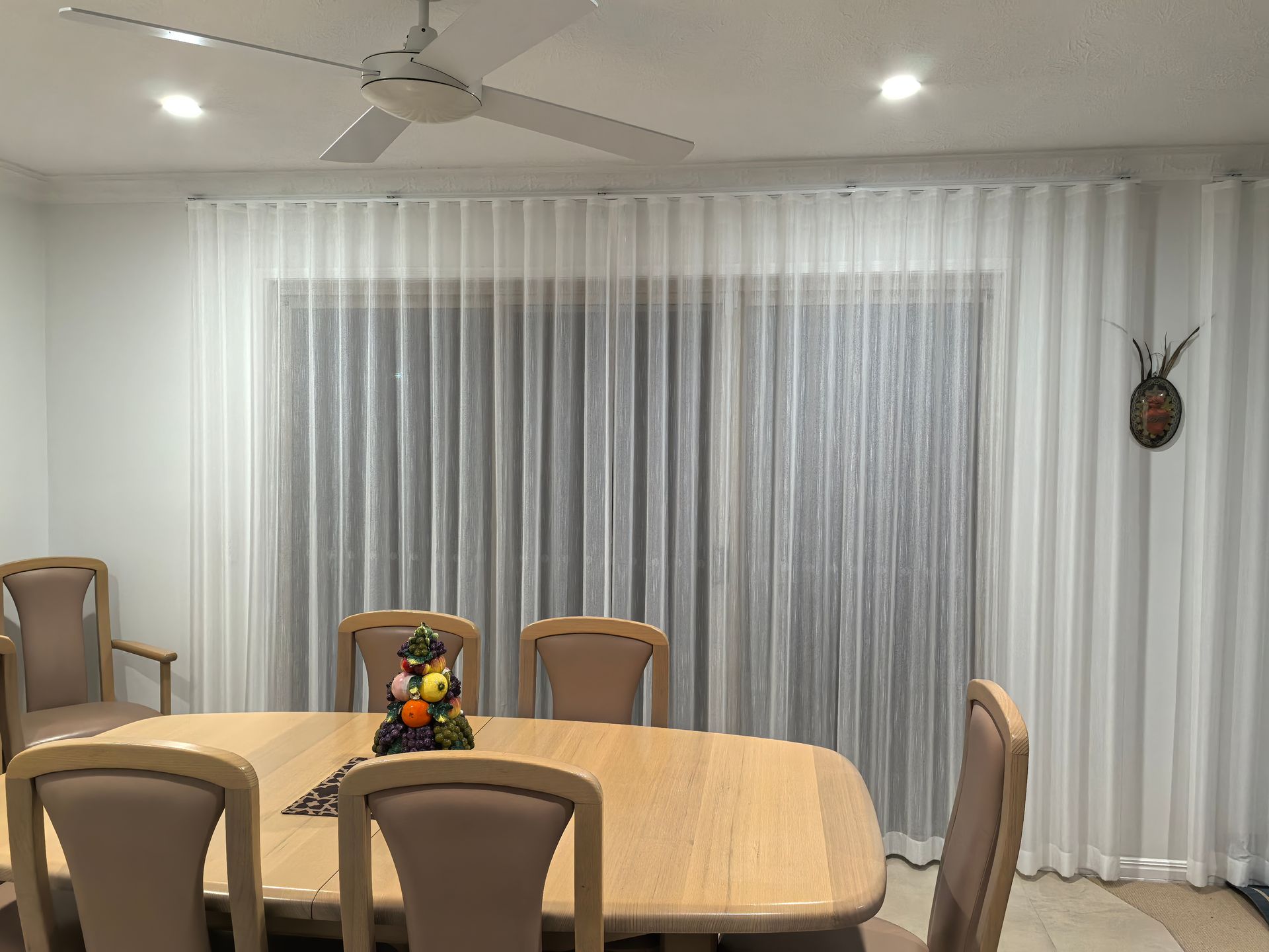 A dining room with a table and chairs and a ceiling fan.