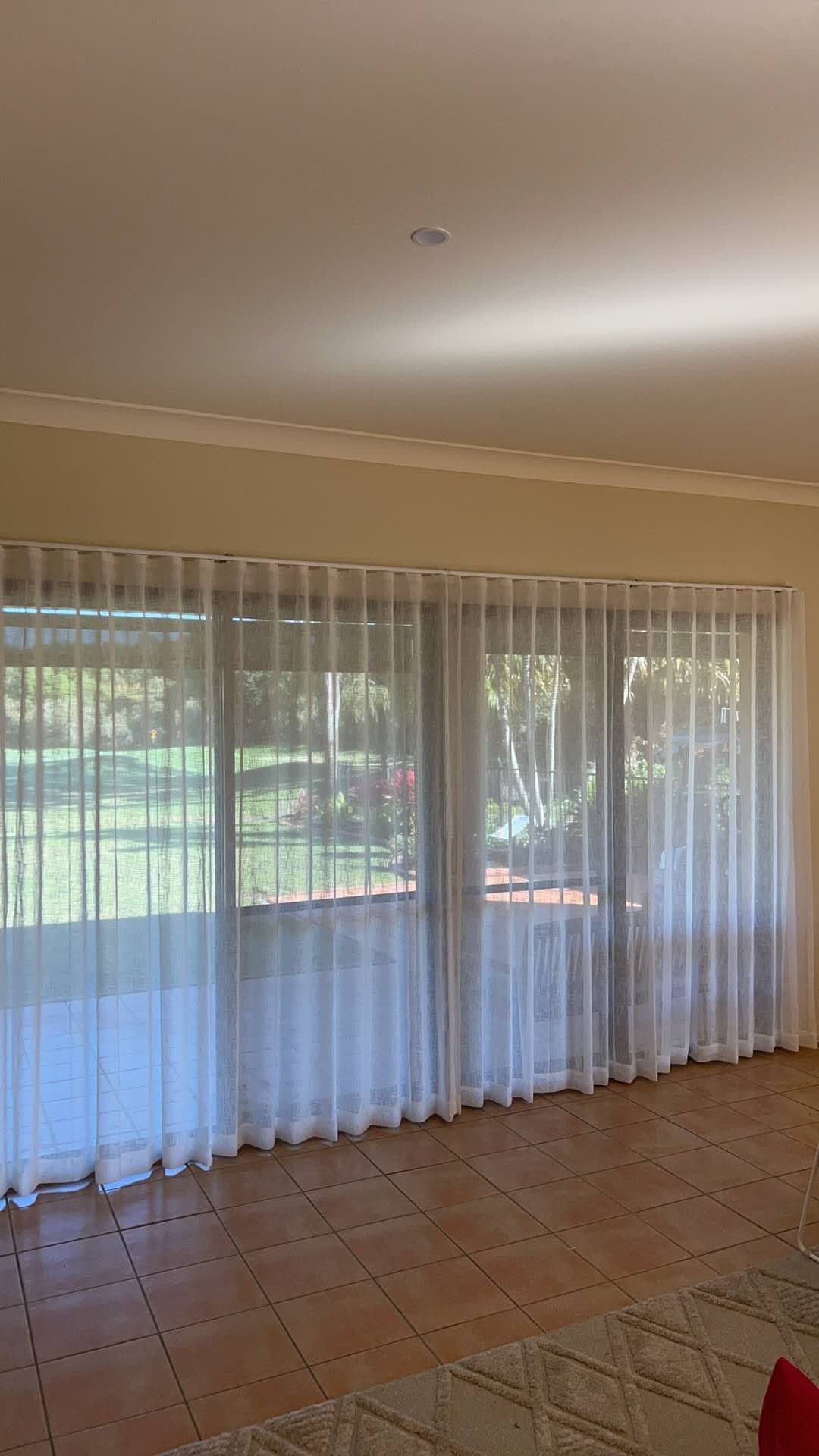 A living room with a sliding glass door and white curtains.