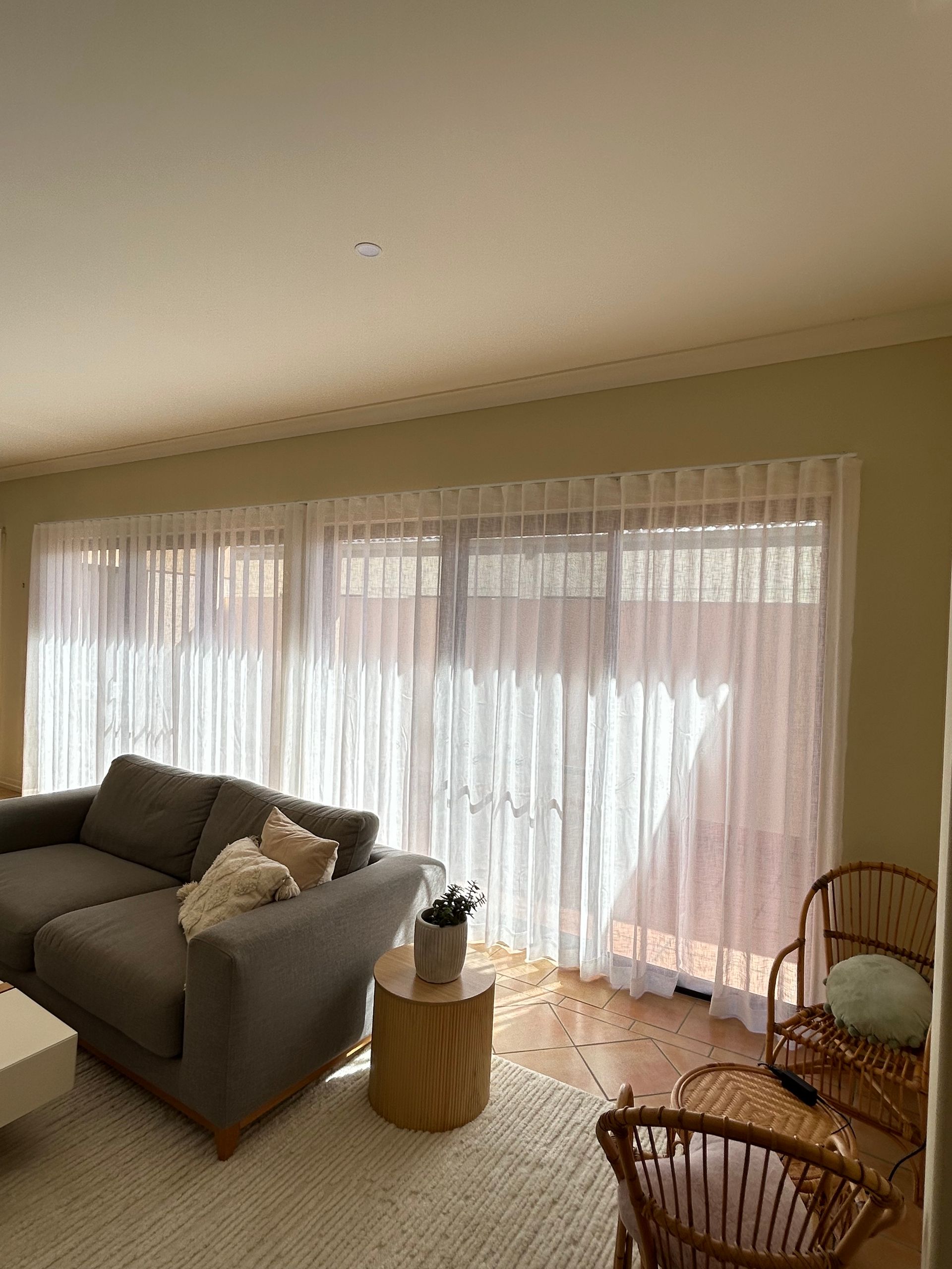 A living room with a couch , chair , table and curtains.