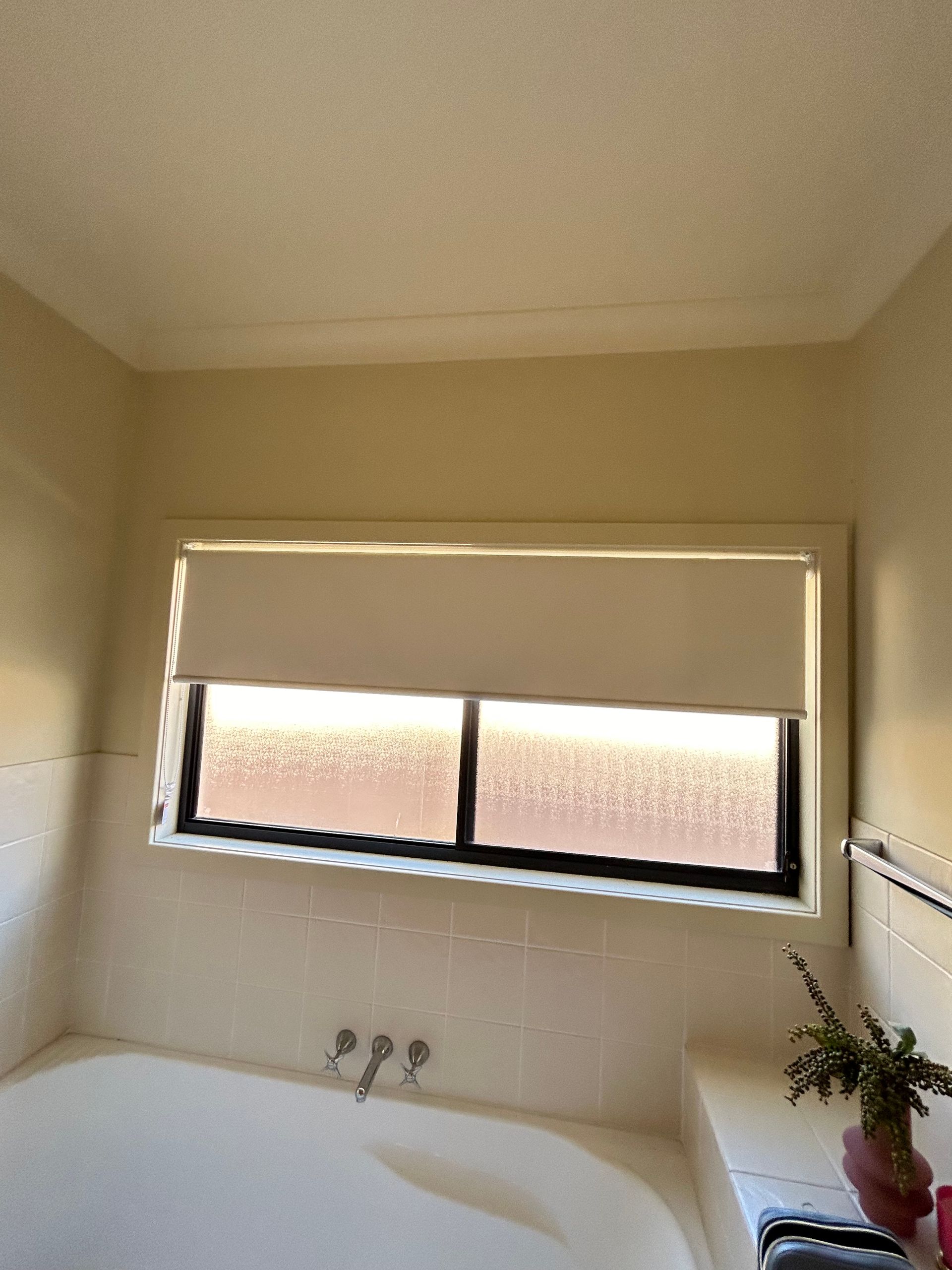 A bathroom with a tub and a window with blinds.