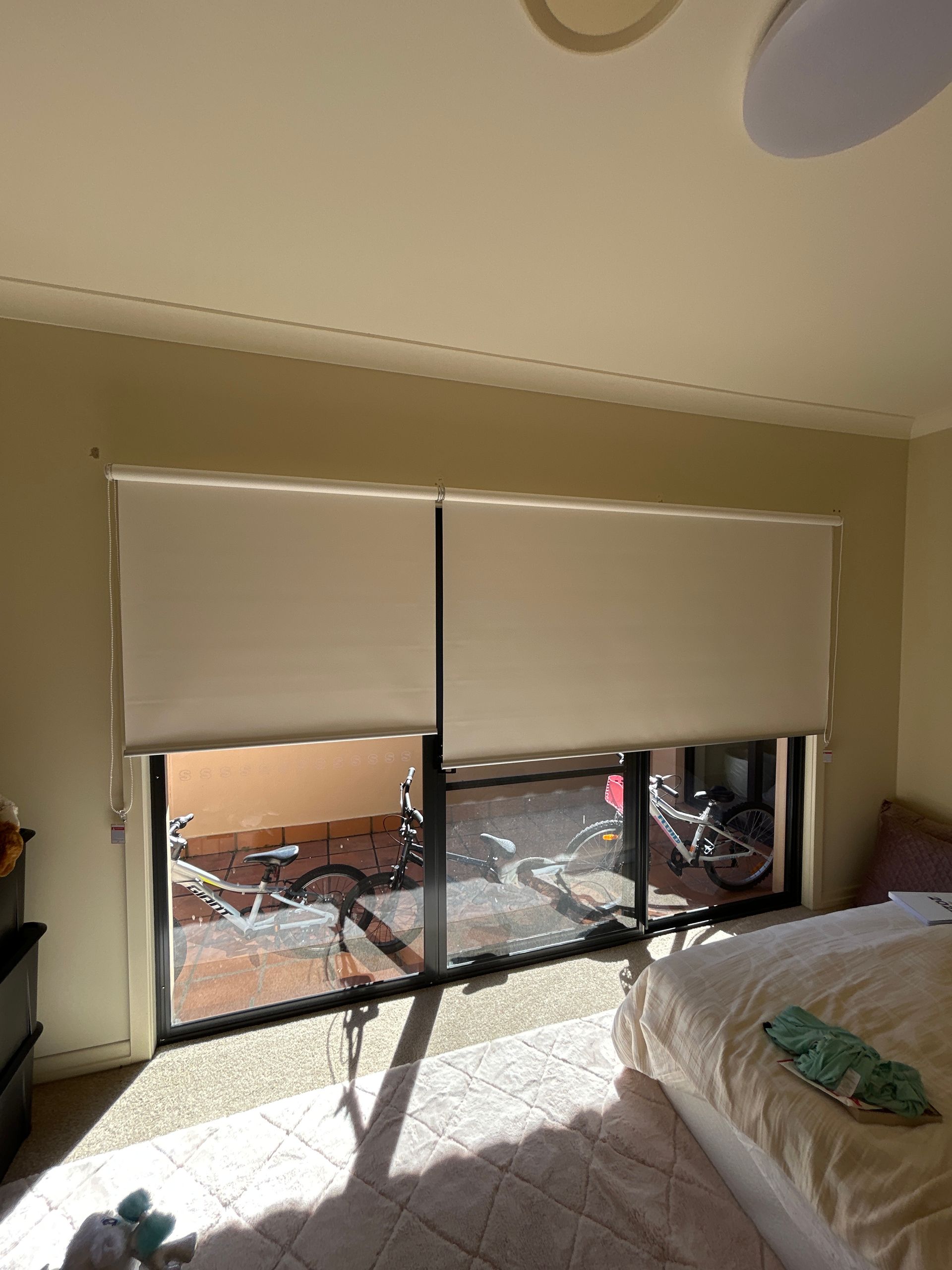 A bedroom with a bed and a sliding glass door with blinds on it.