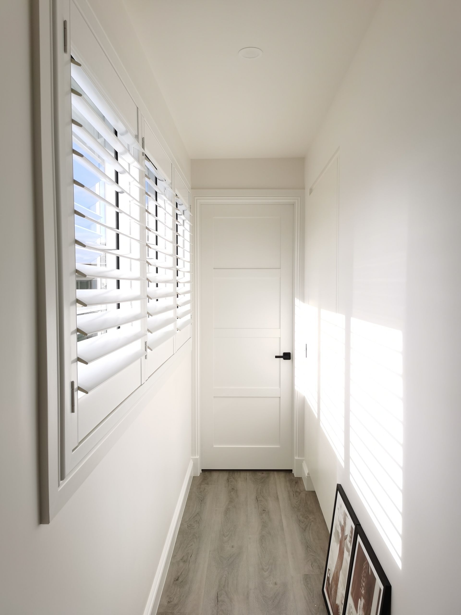 A hallway with shutters on the windows and a door
