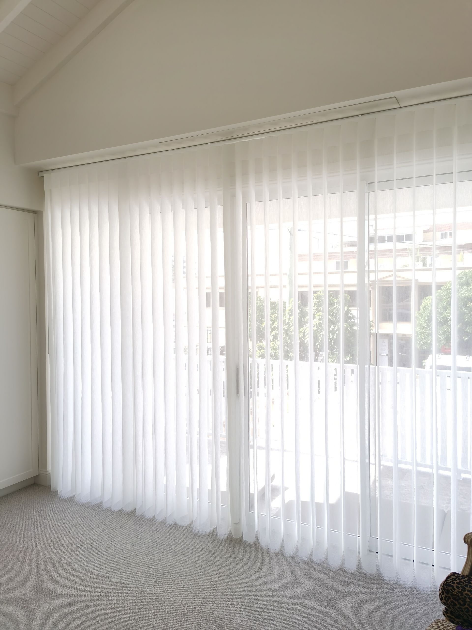 A living room with sliding glass doors and white vertical blinds.
