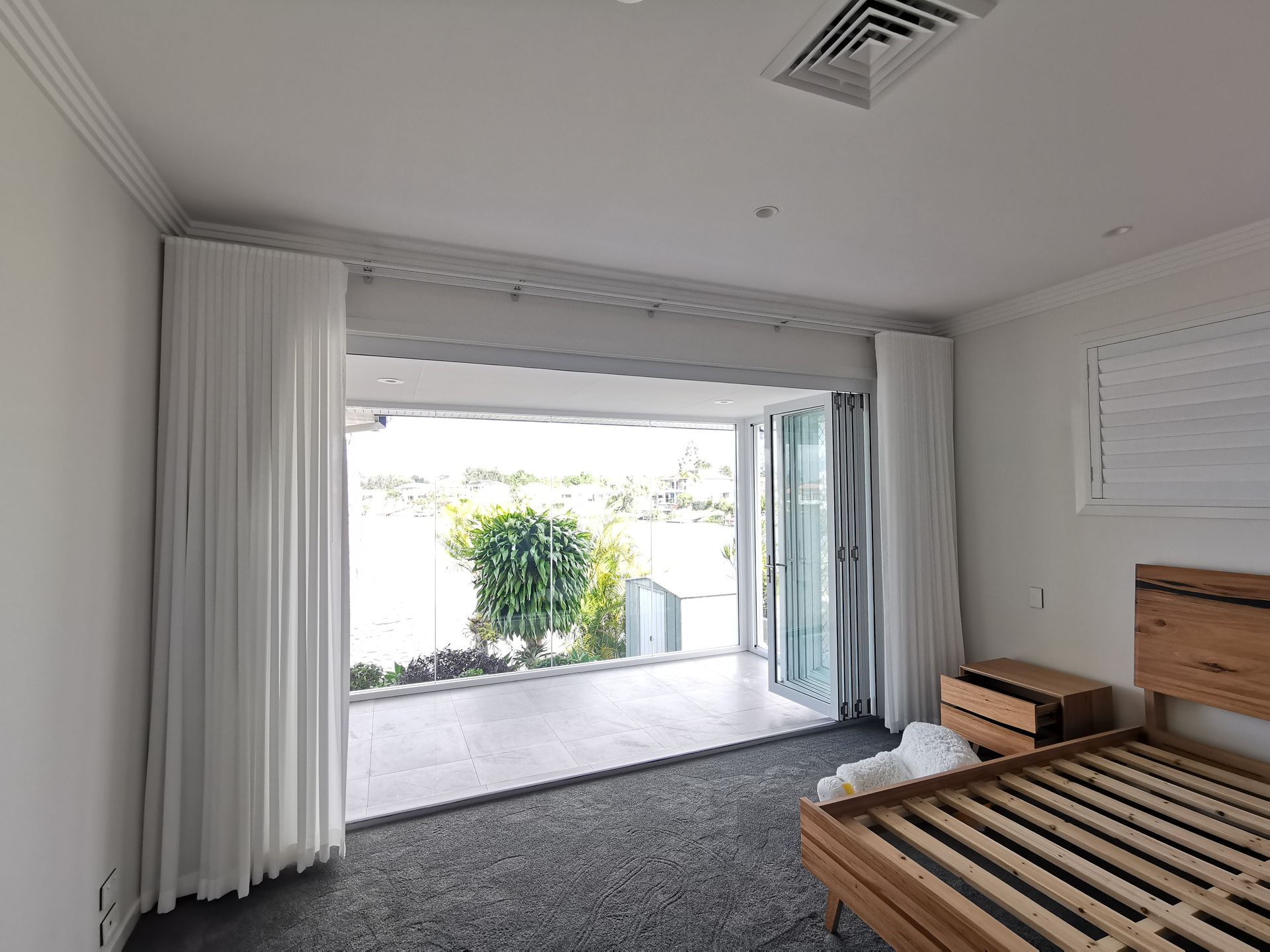 A bedroom with a bed , nightstand , and sliding glass doors.