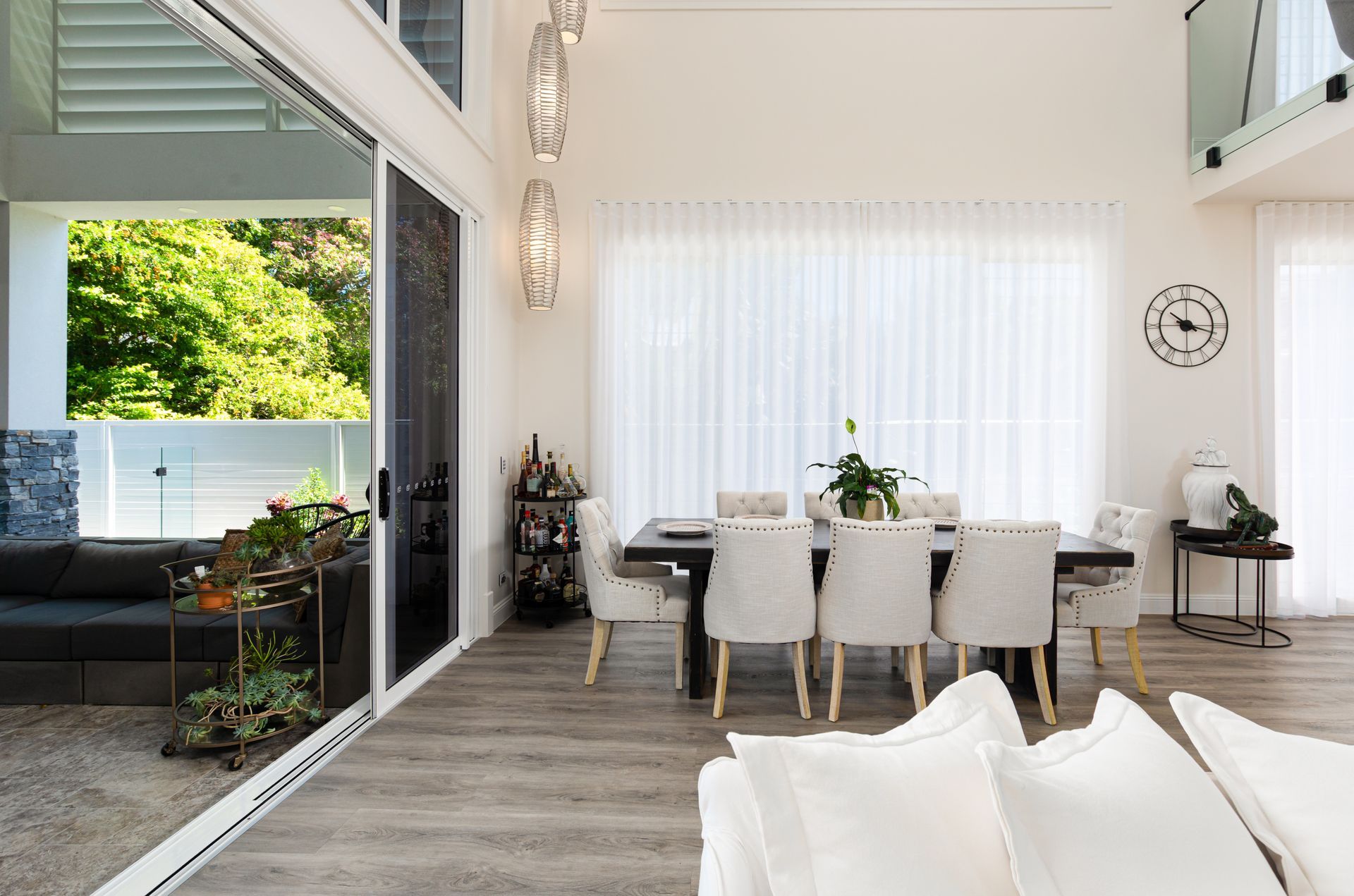 A living room with a dining table and chairs and a clock on the wall.