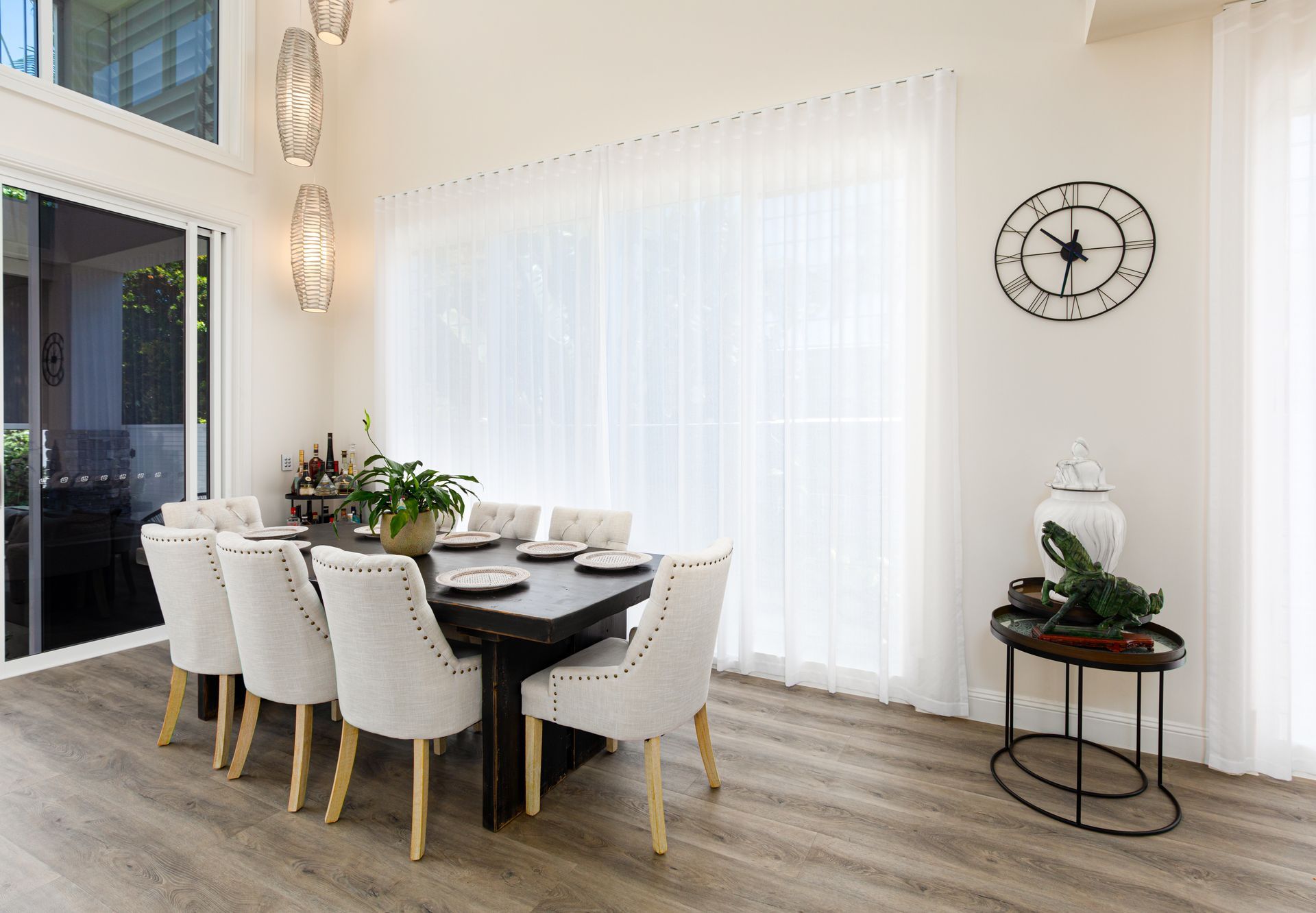 A dining room with a table and chairs and a clock on the wall.
