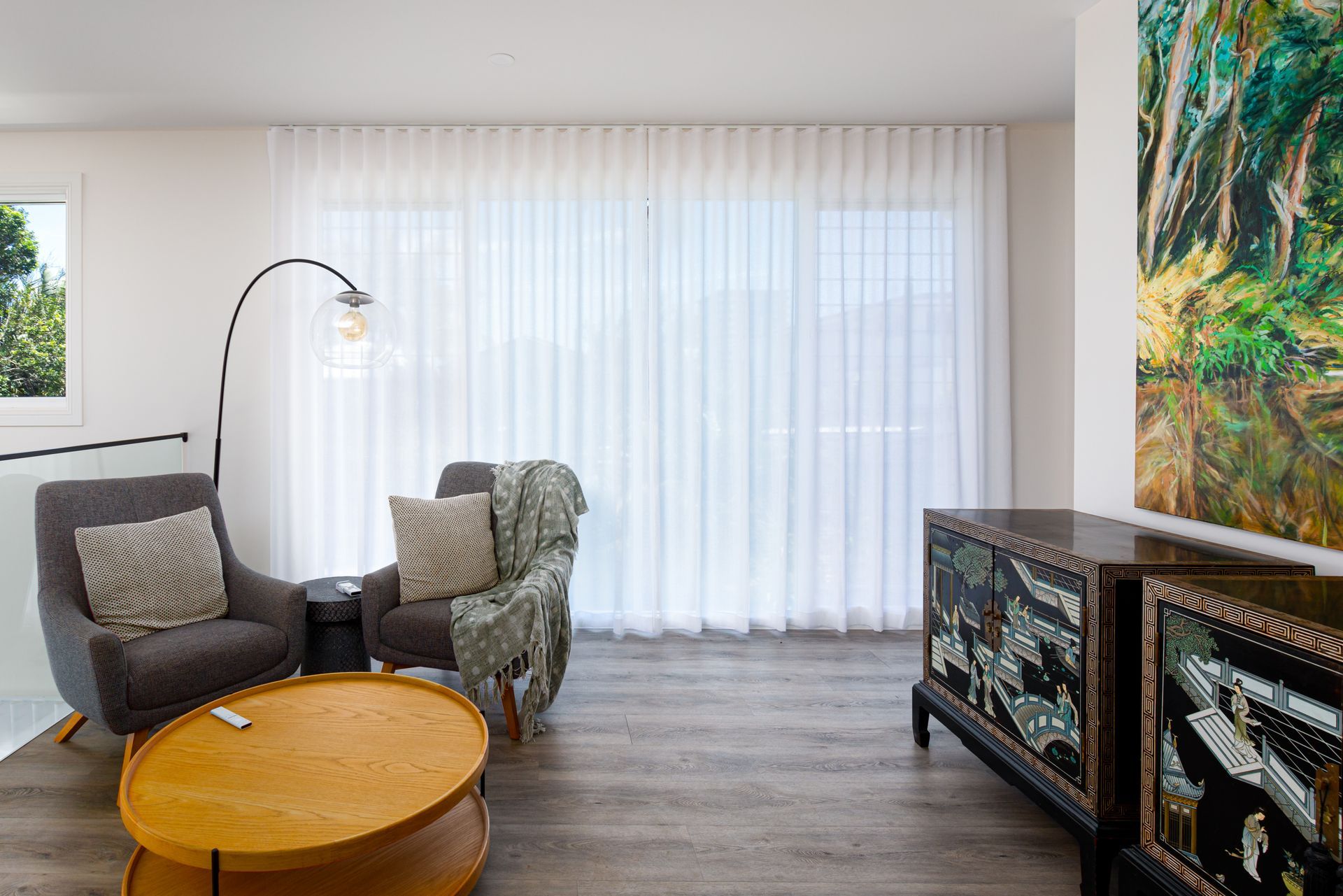 A living room with a table , chairs , and a painting on the wall.