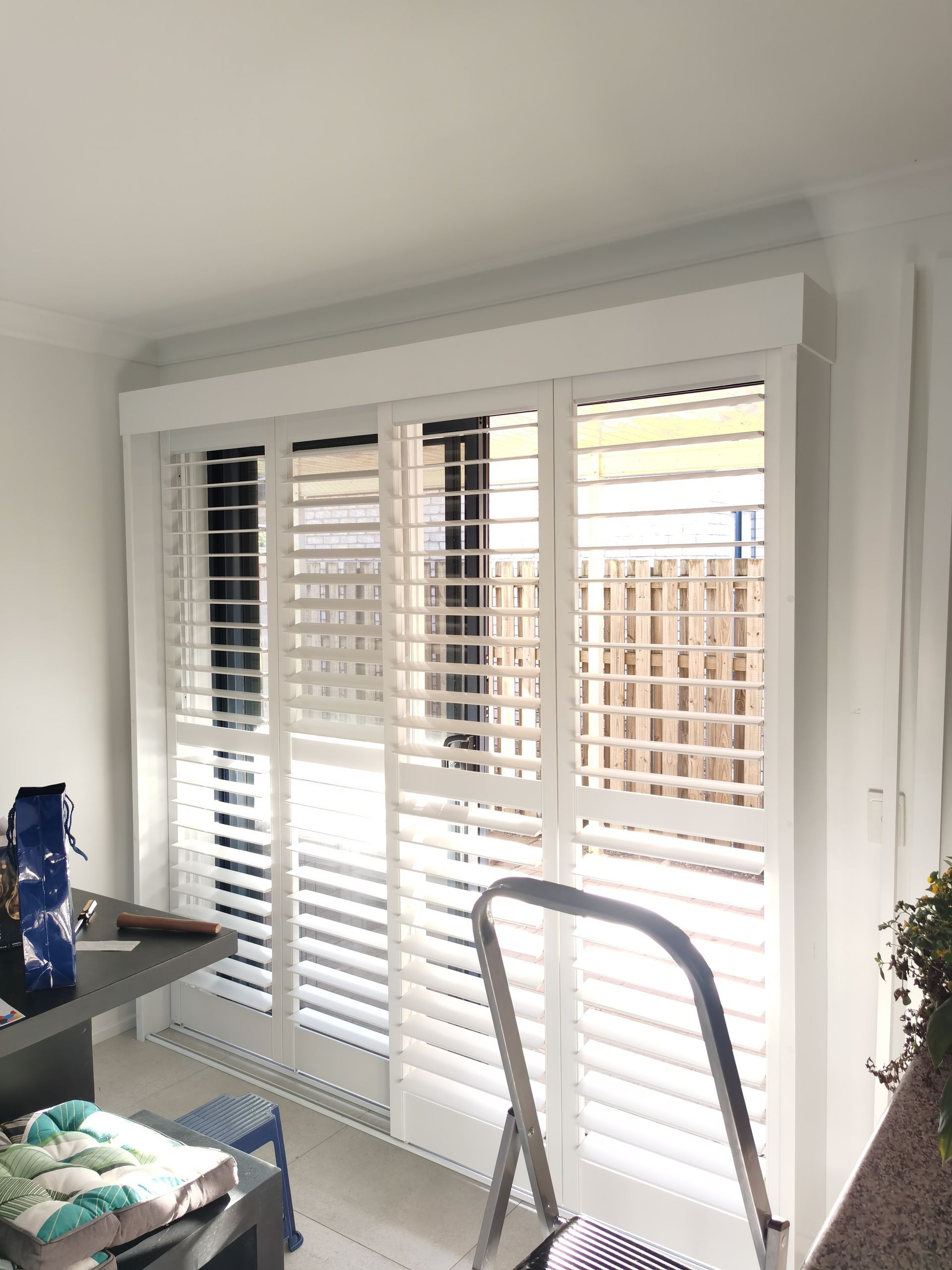 A living room with white shutters on a sliding glass door.