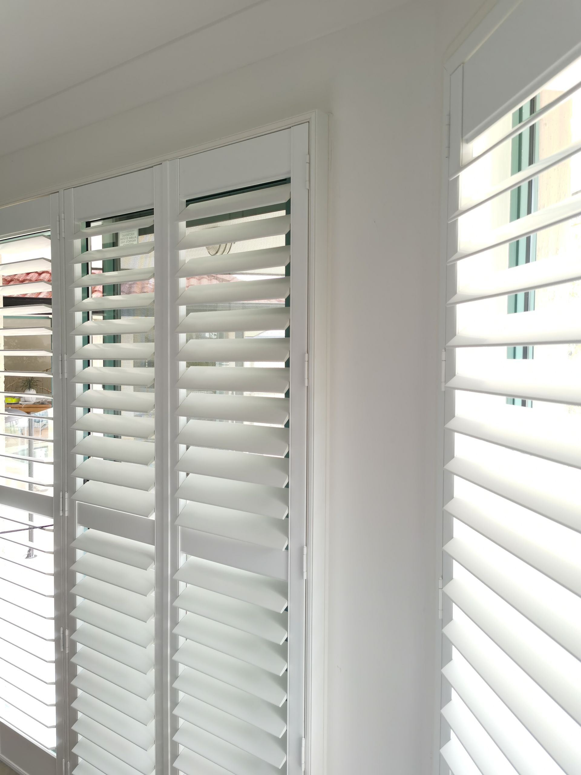 A room with white shutters on the windows