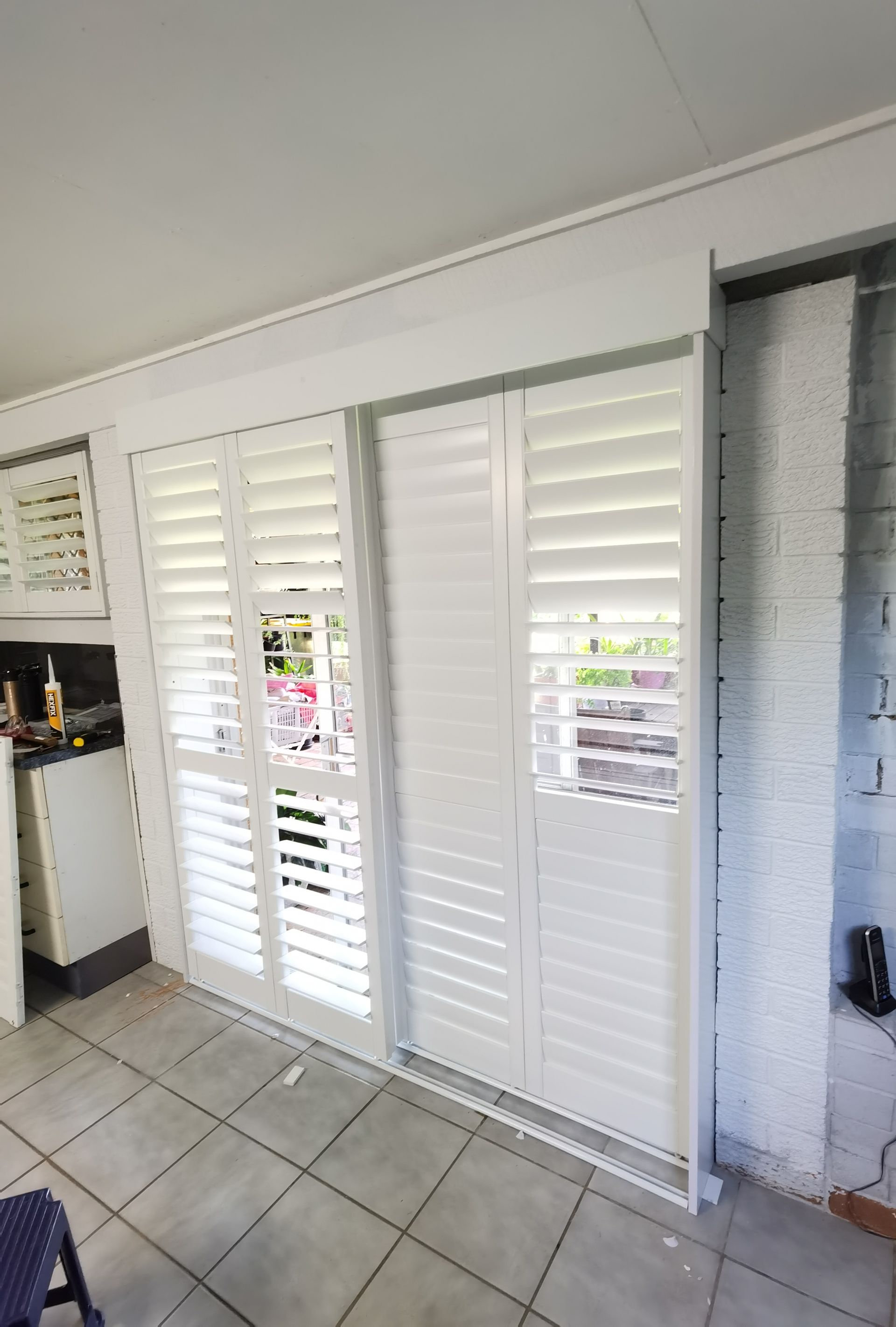 A kitchen with sliding glass doors and white shutters on them.