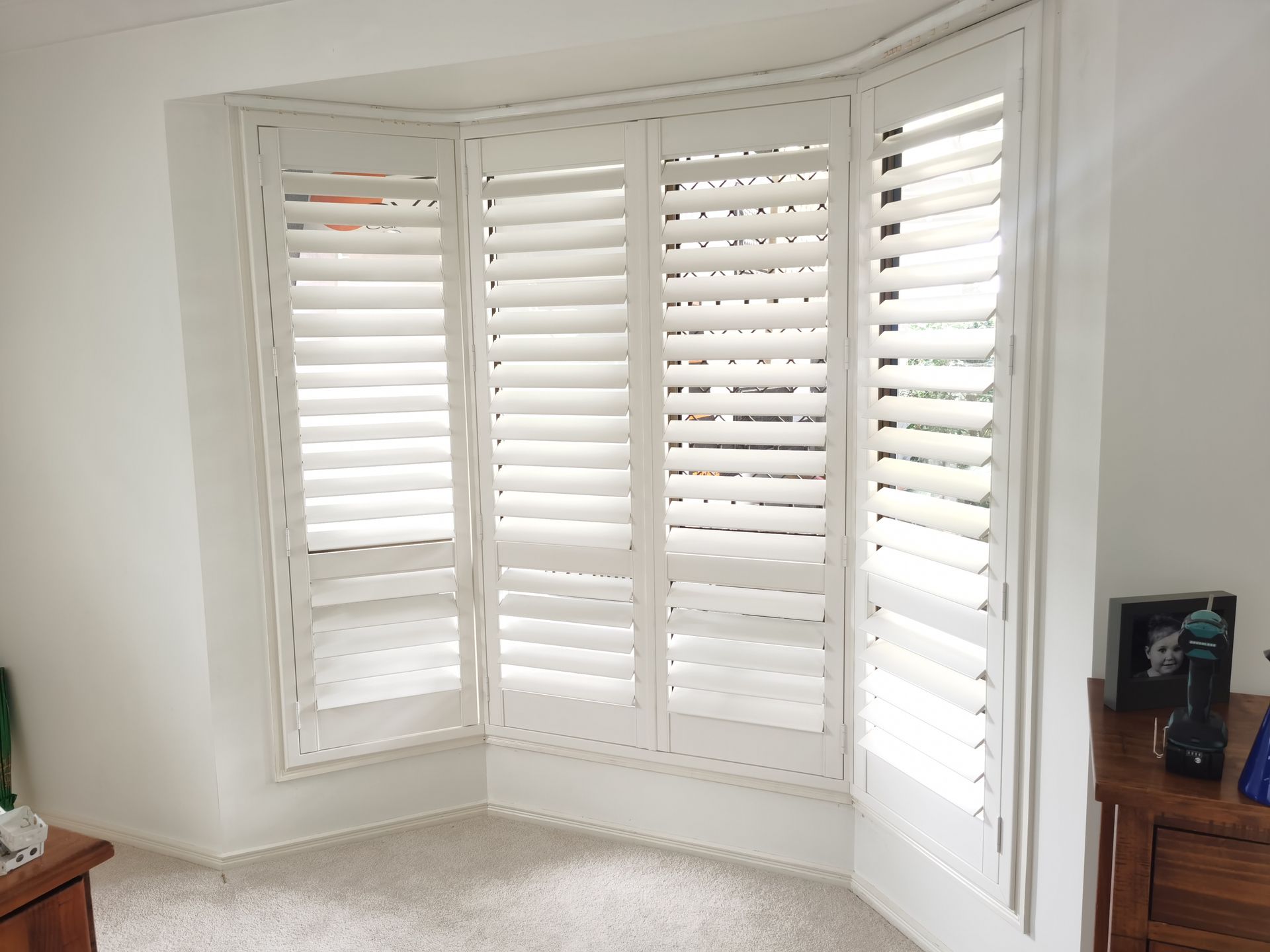 A living room with white shutters on a bay window.