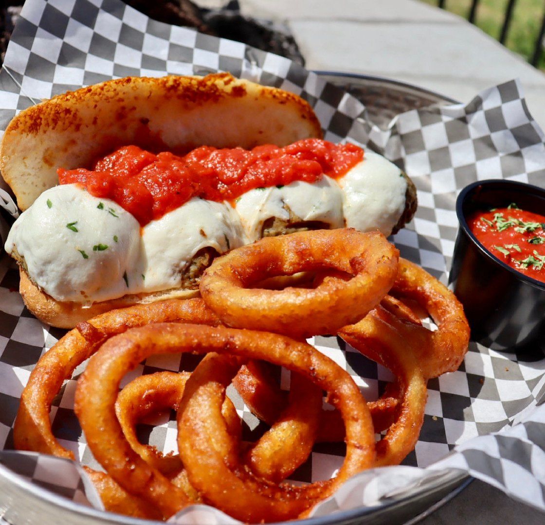 A plate of food with onion rings and a dipping sauce