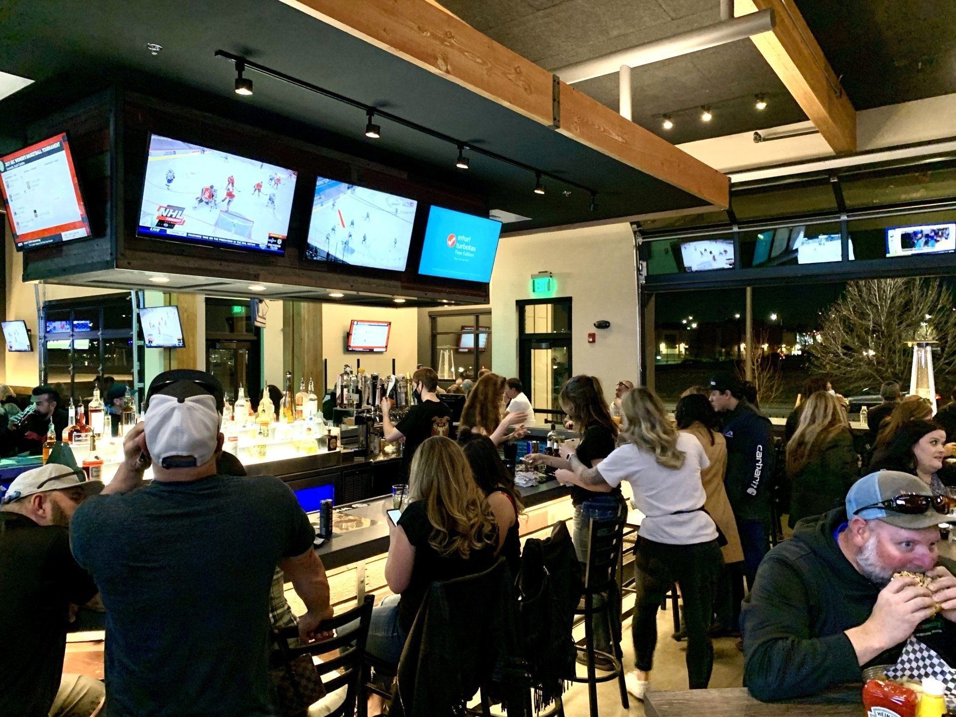 A group of people are sitting at a bar in a restaurant.