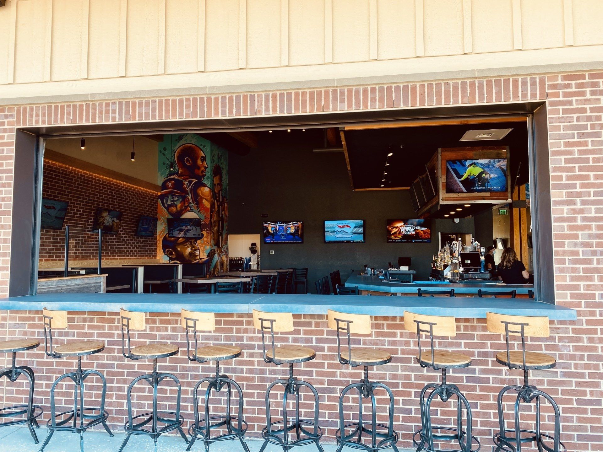 A brick building with a bar and stools in front of it.