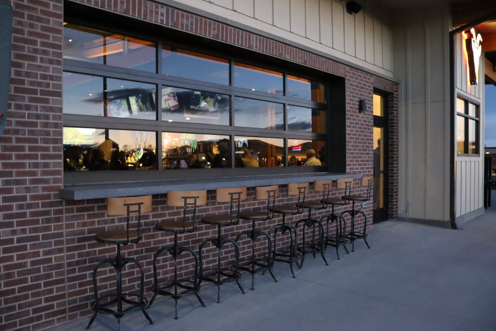 A row of bar stools are lined up in front of a brick building.