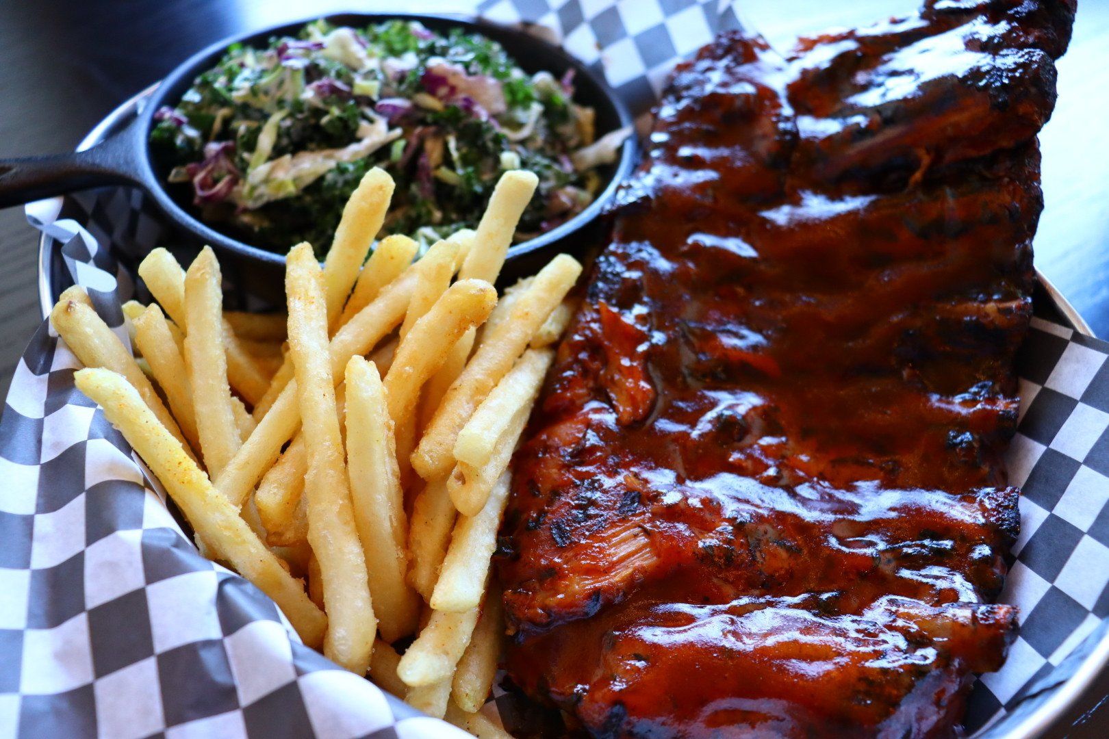 A plate of ribs and french fries on a checkered paper