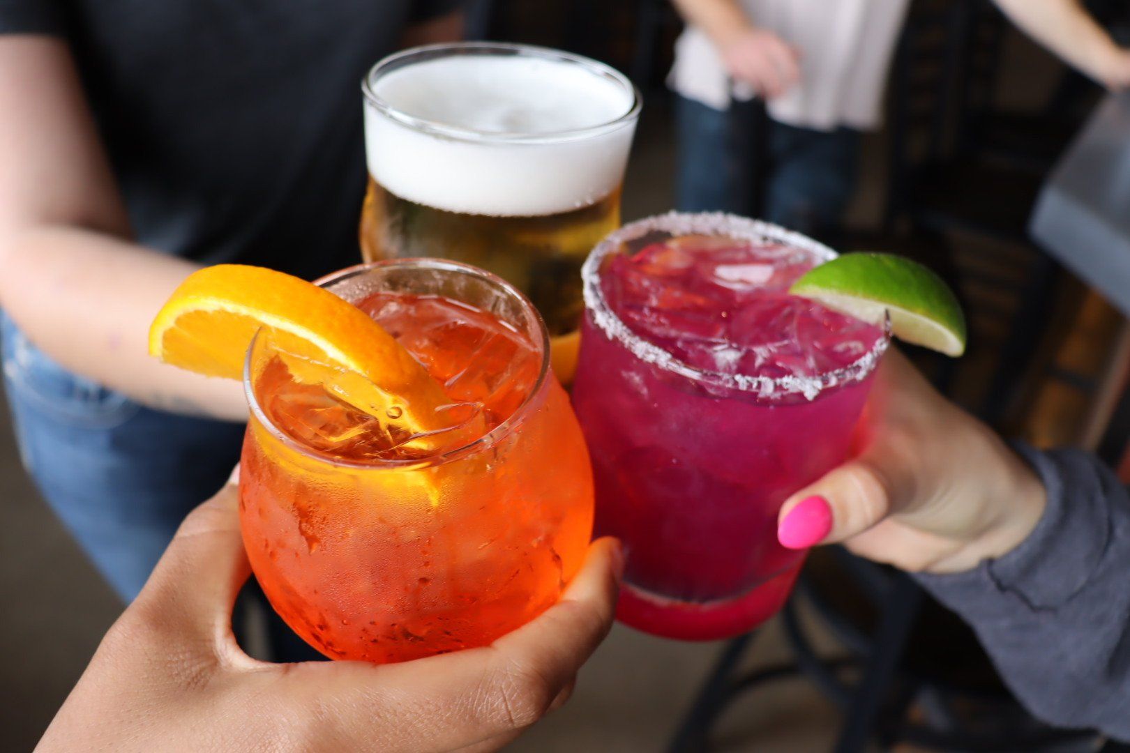 A group of people are toasting with three different drinks.