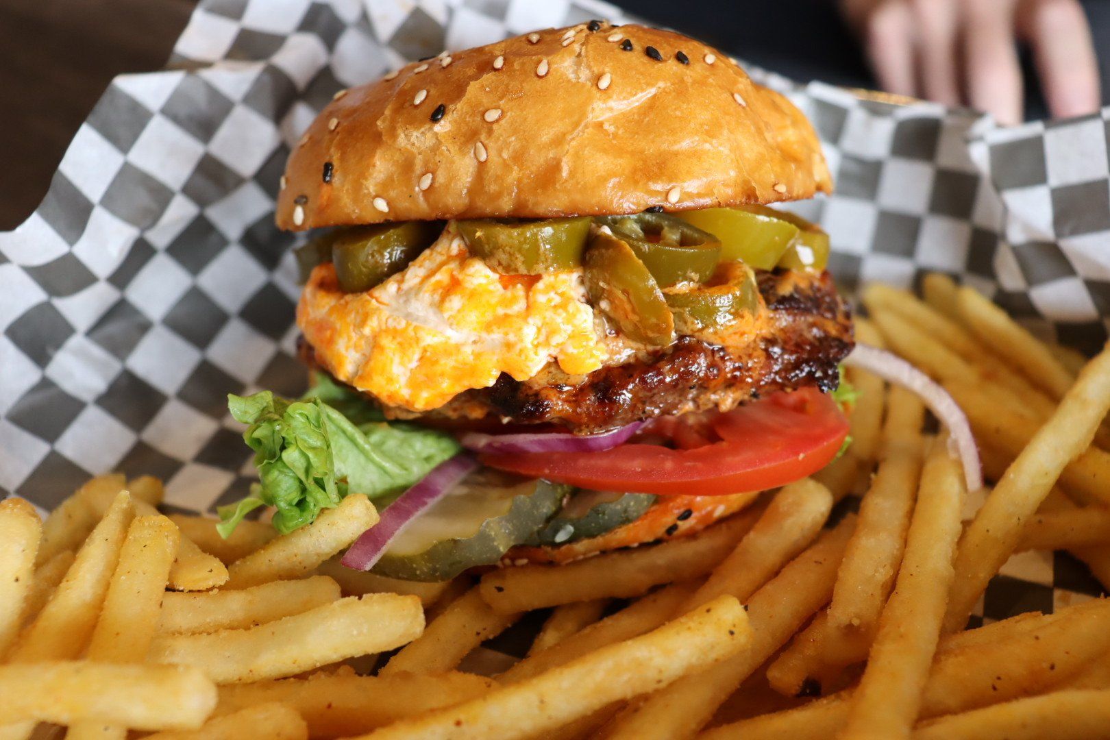 A hamburger is sitting on top of a basket of french fries.