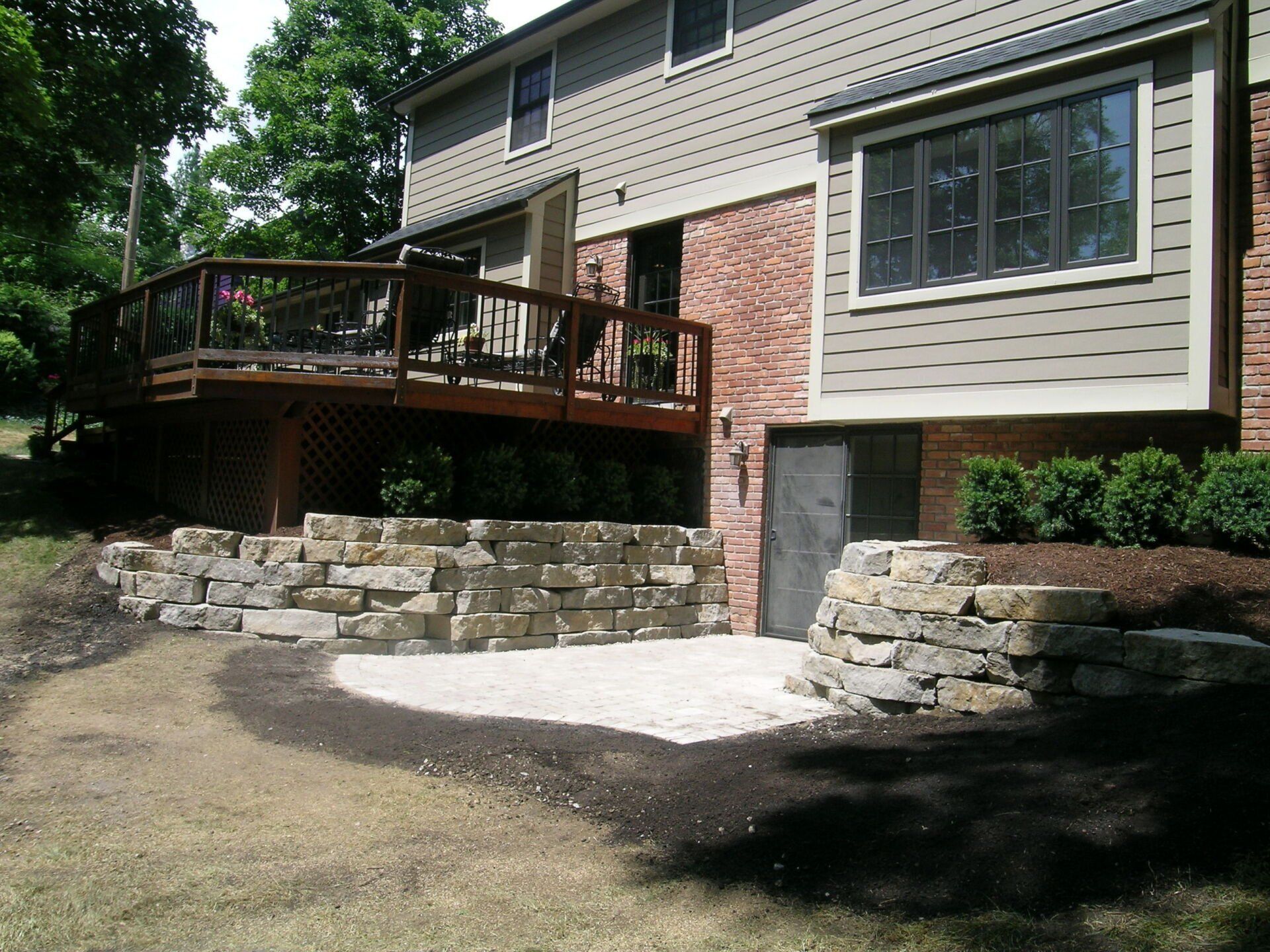 A house with a deck and a stone wall in front of it