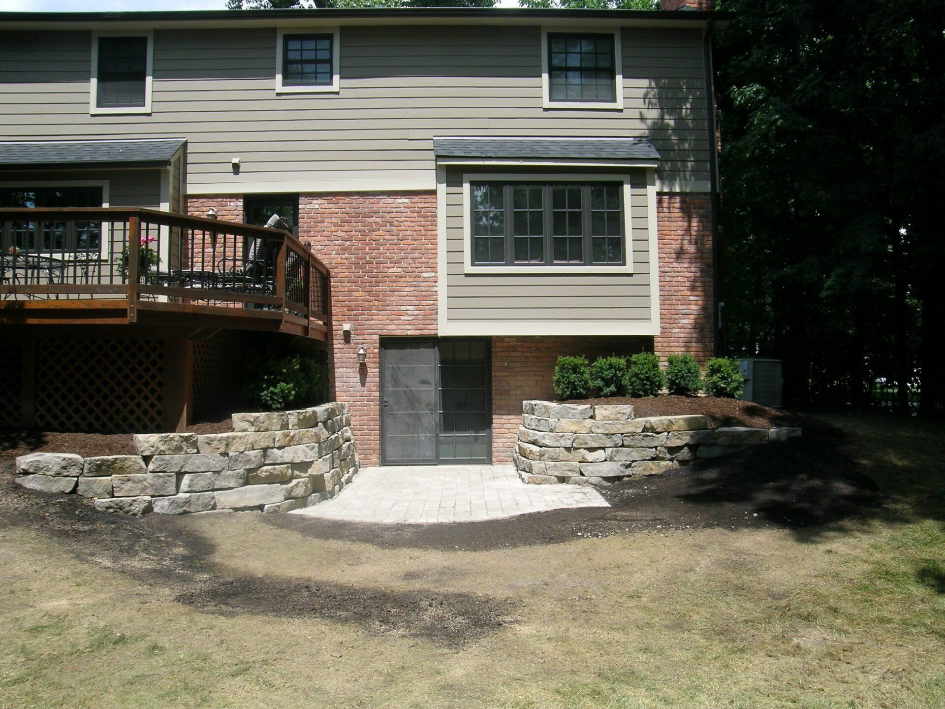 A house with a deck and a stone wall