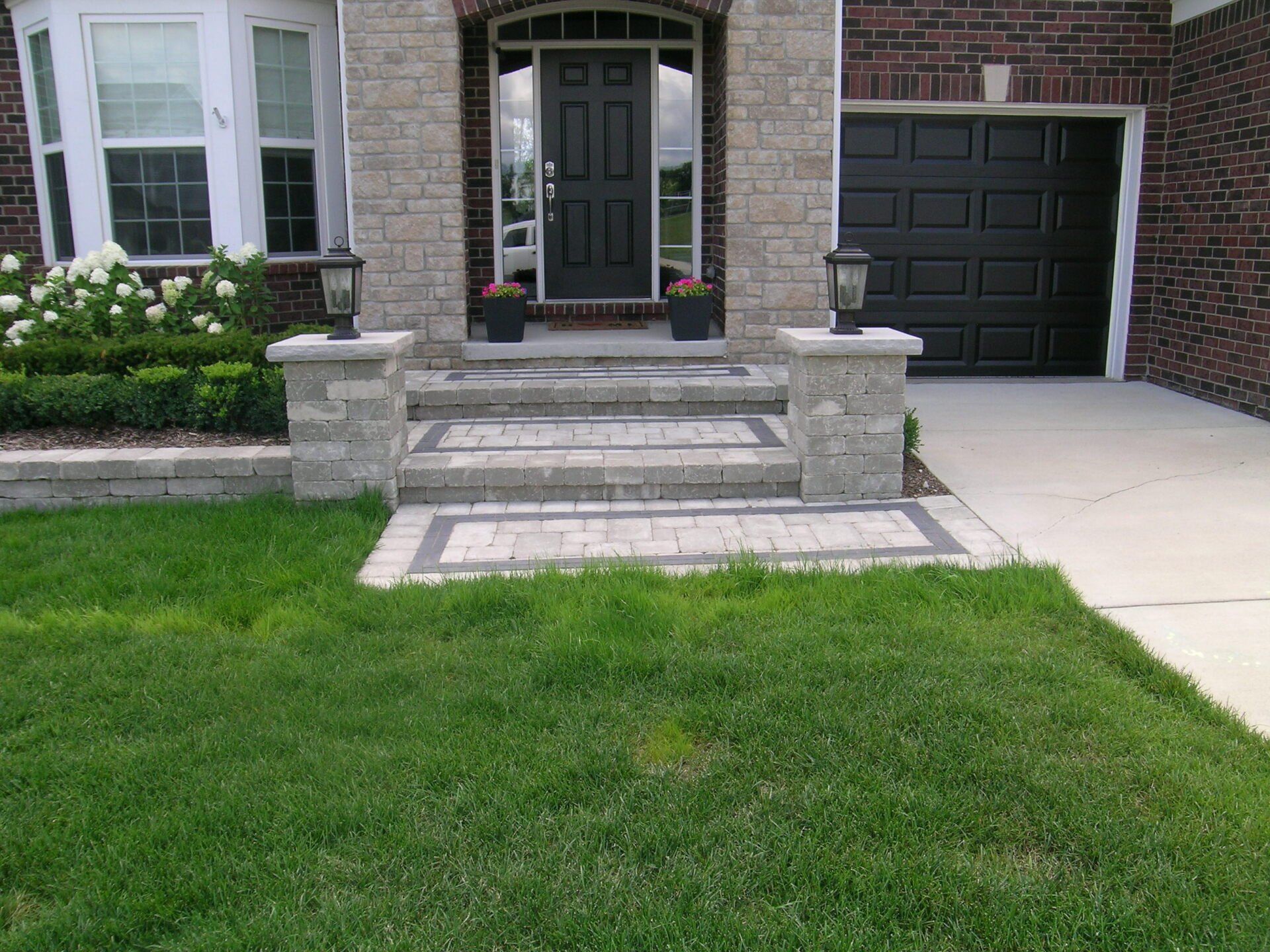 A brick house with a black garage door and steps