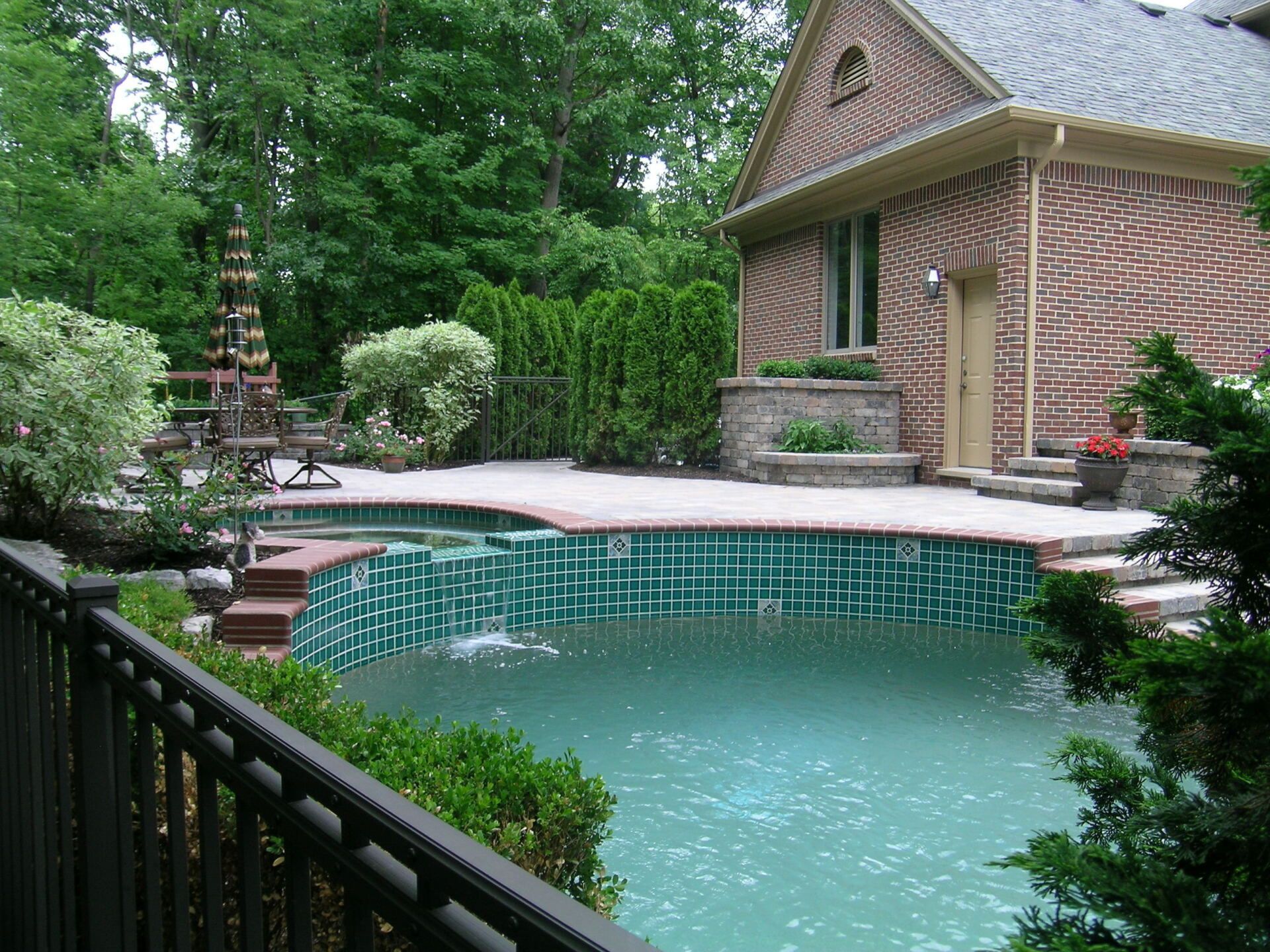 A brick house with a large swimming pool in front of it