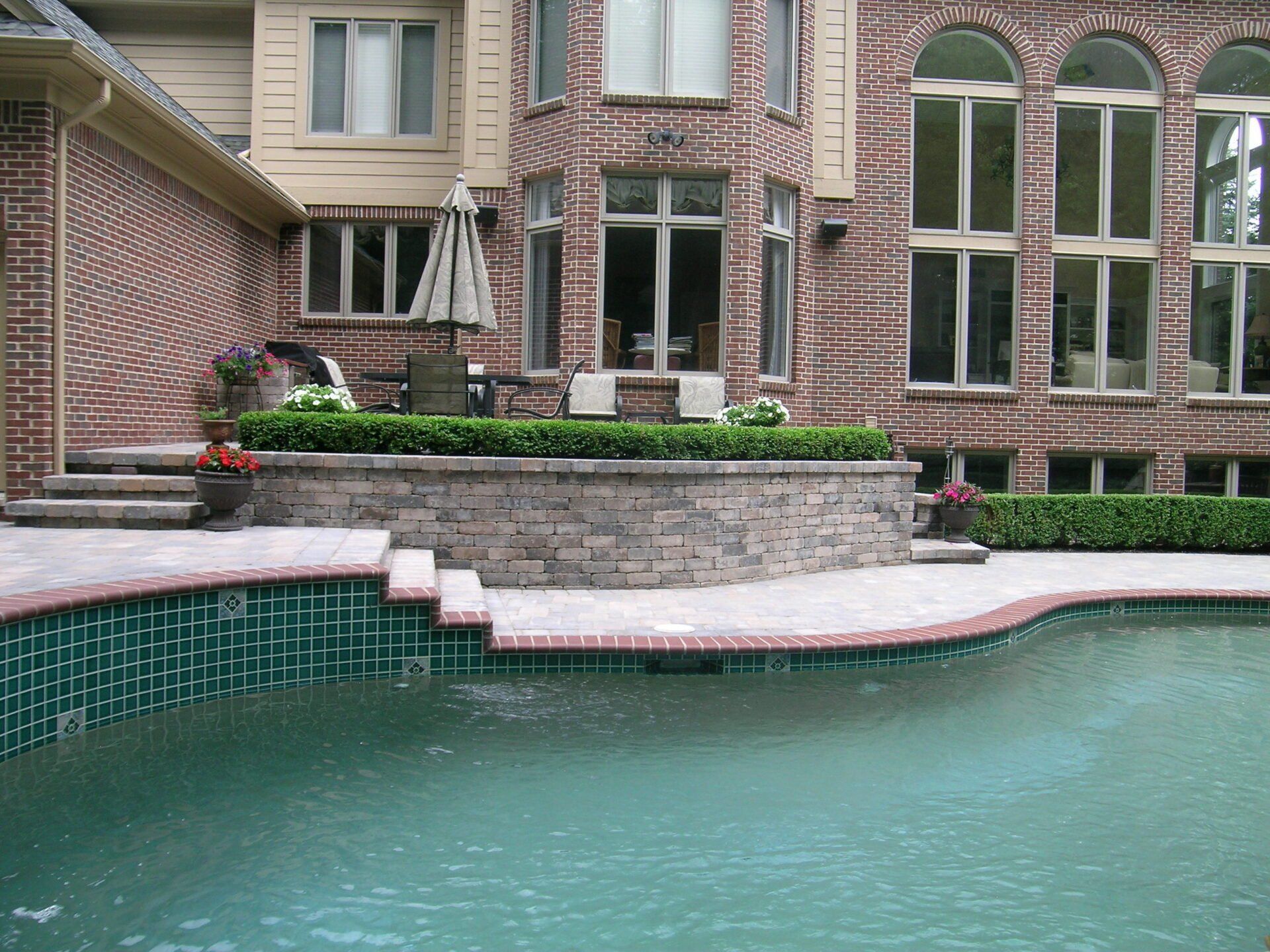 A large brick house with a swimming pool in front of it