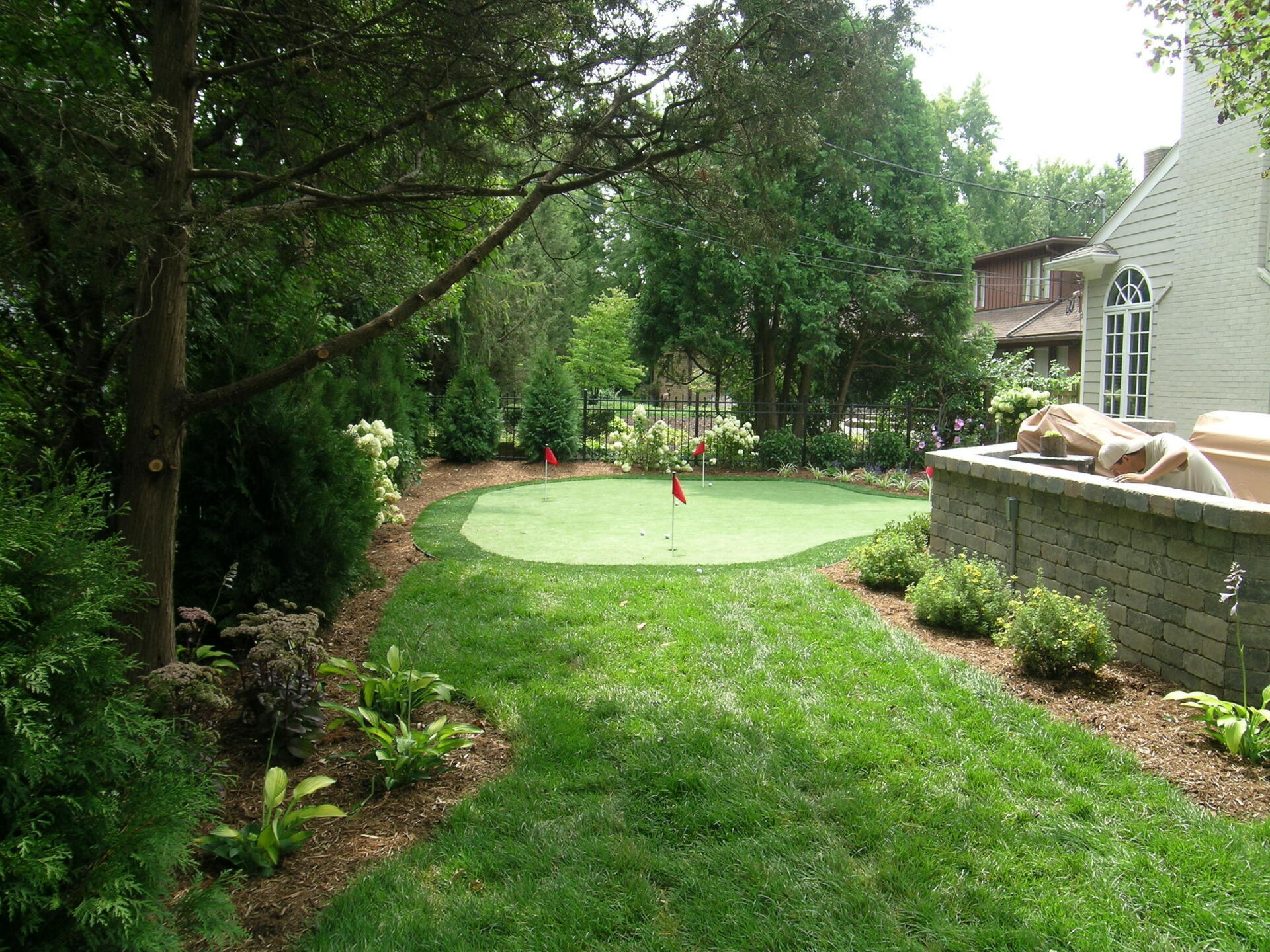 There is a putting green in the backyard of a house.