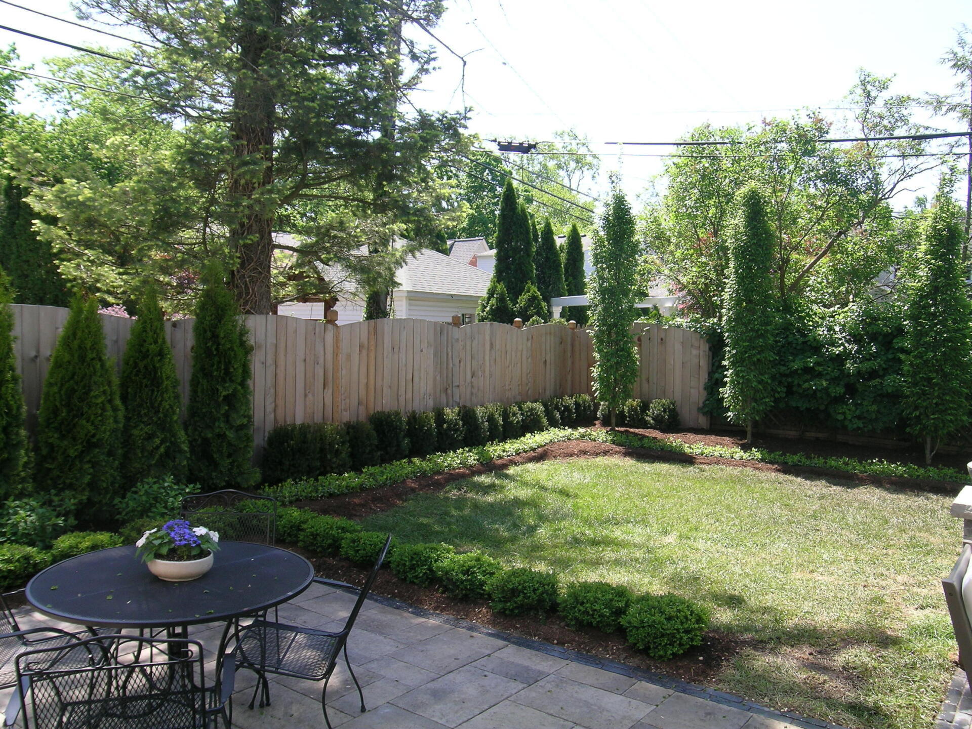 A backyard with a table and chairs and a wooden fence