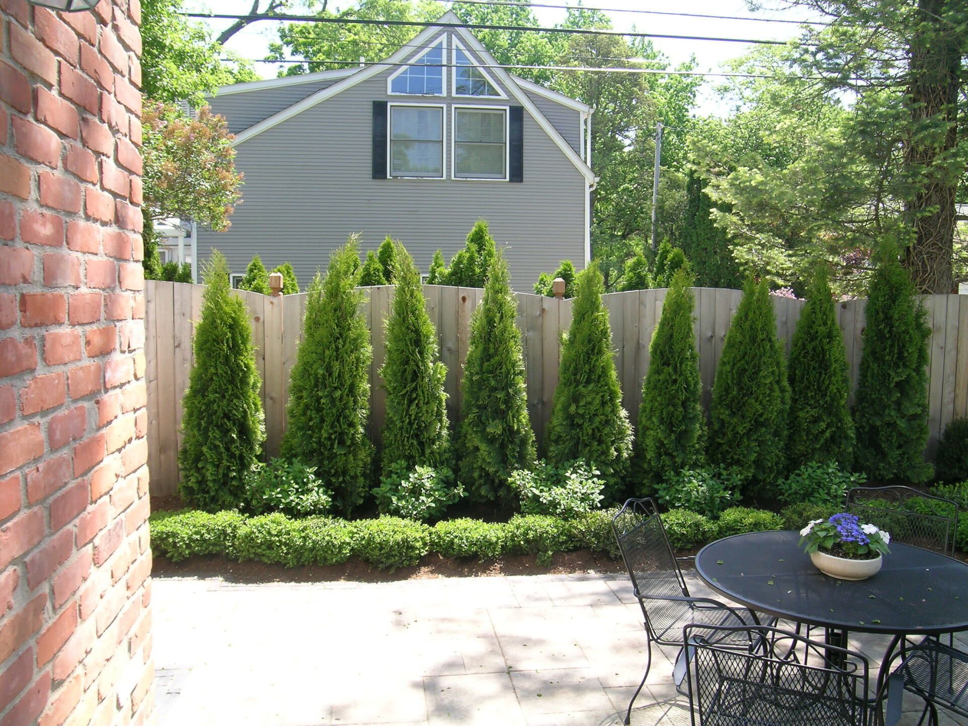 A patio with a table and chairs surrounded by trees and bushes