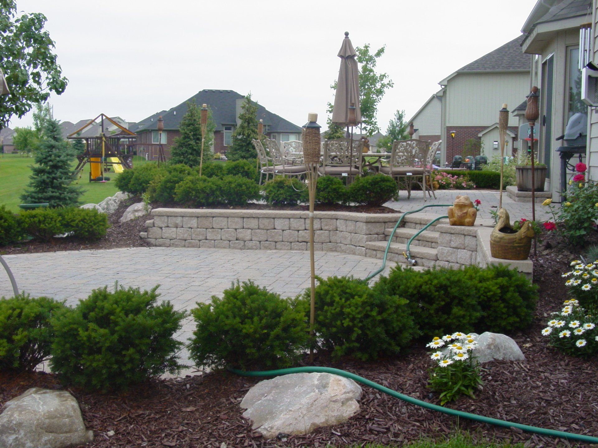 A hose is connected to a brick wall in a backyard