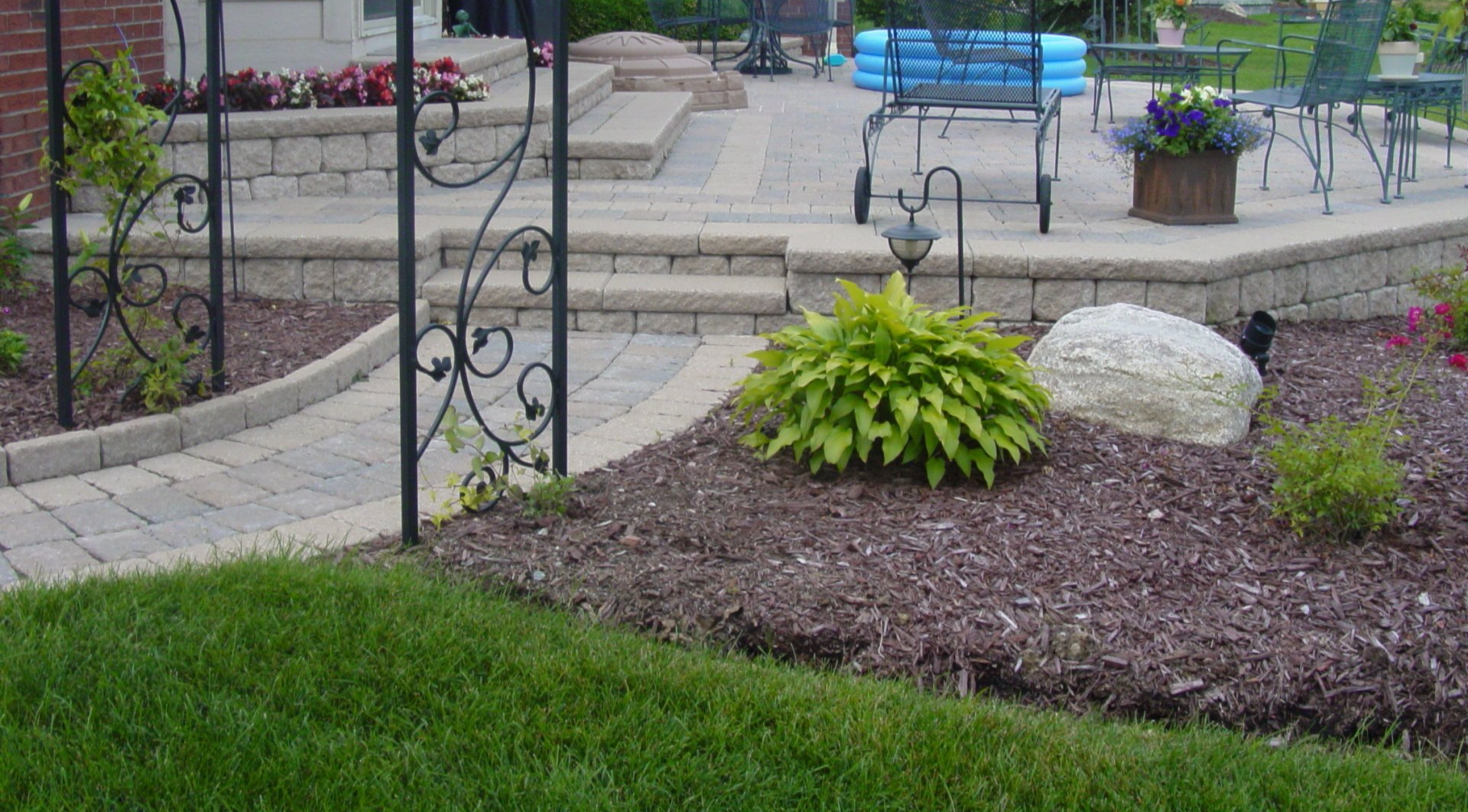 A lush green lawn with a patio in the background