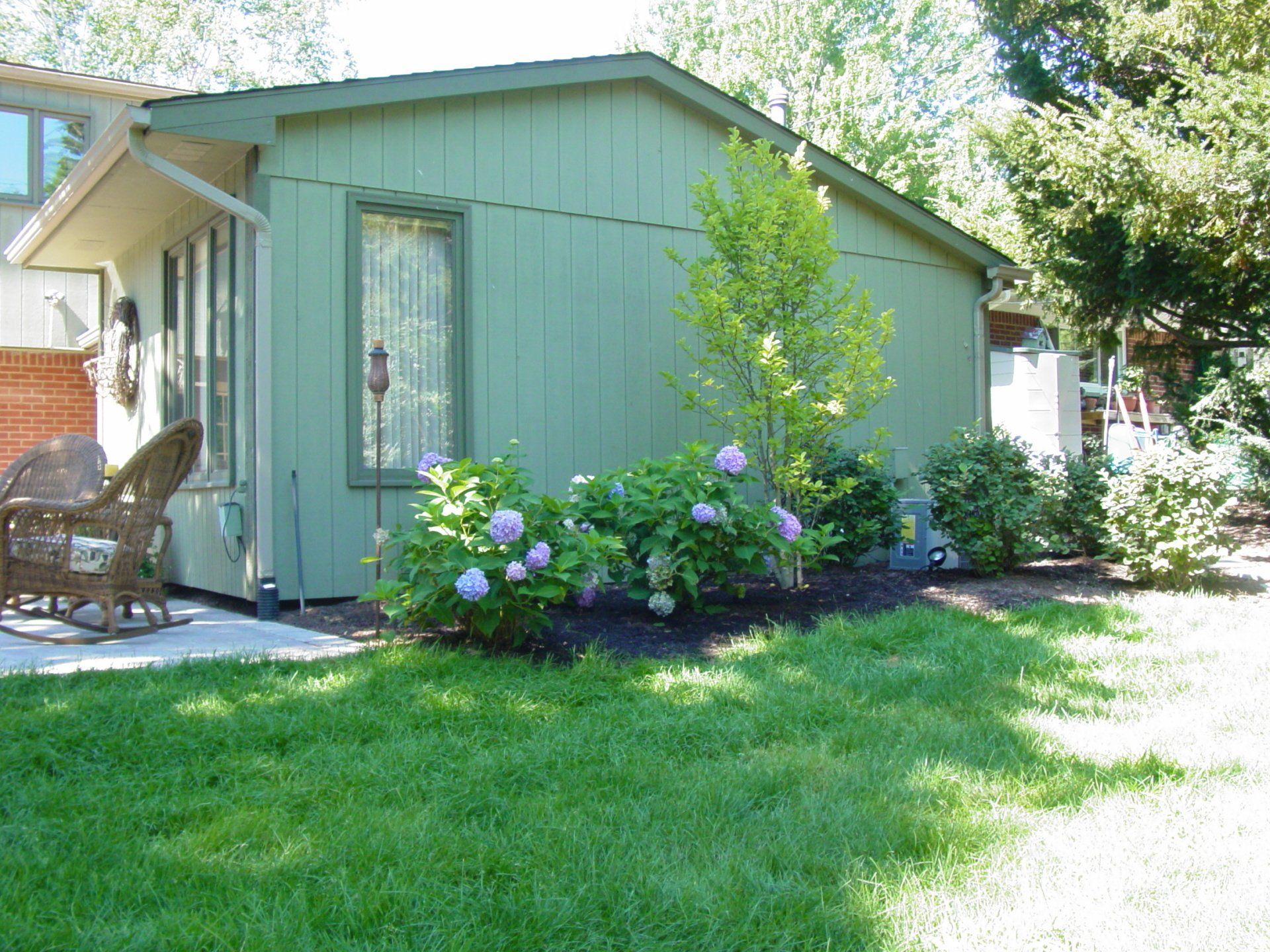 A green house with a rocking chair in front of it