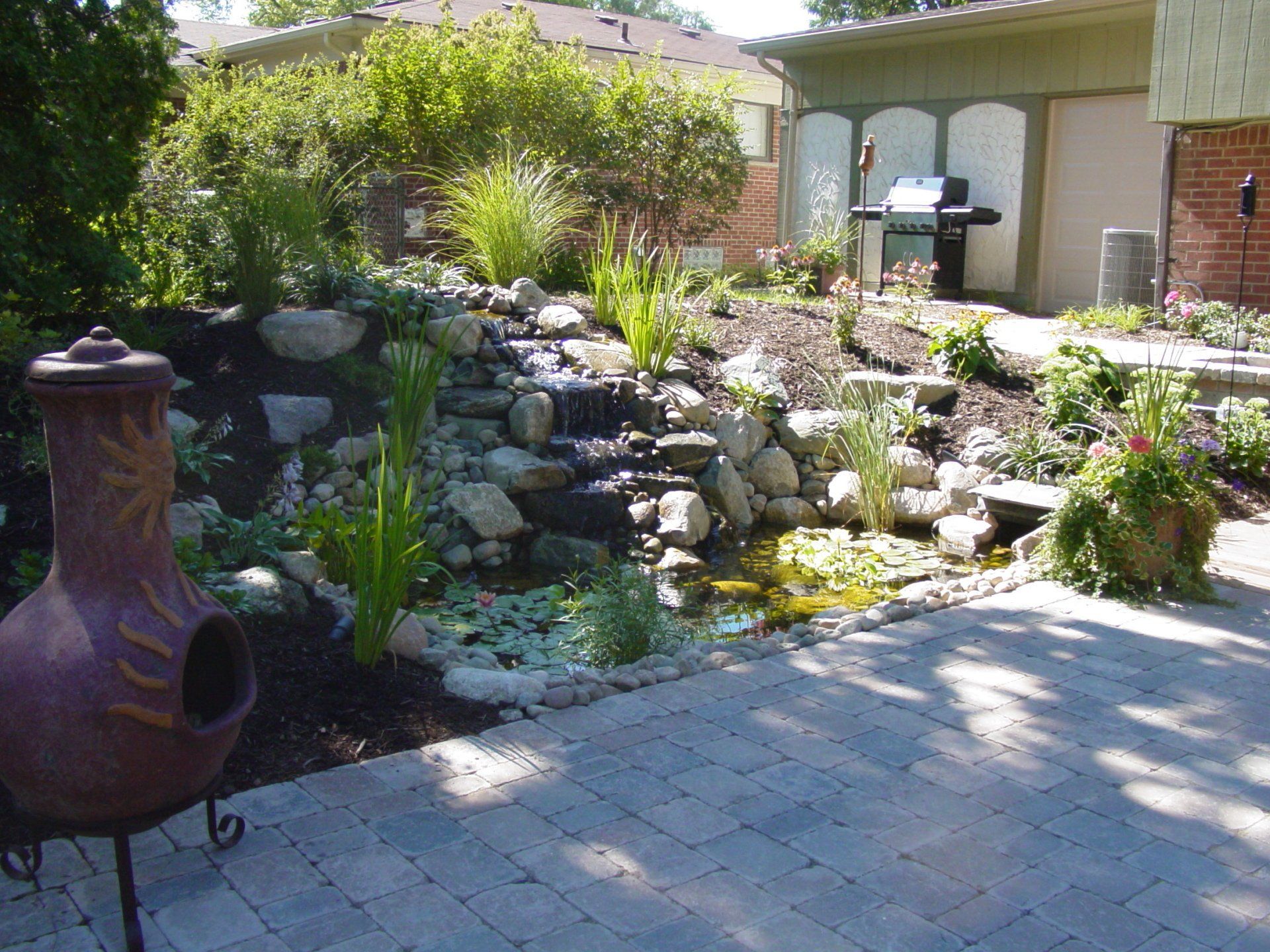 A patio with a fire pit and a waterfall in the background