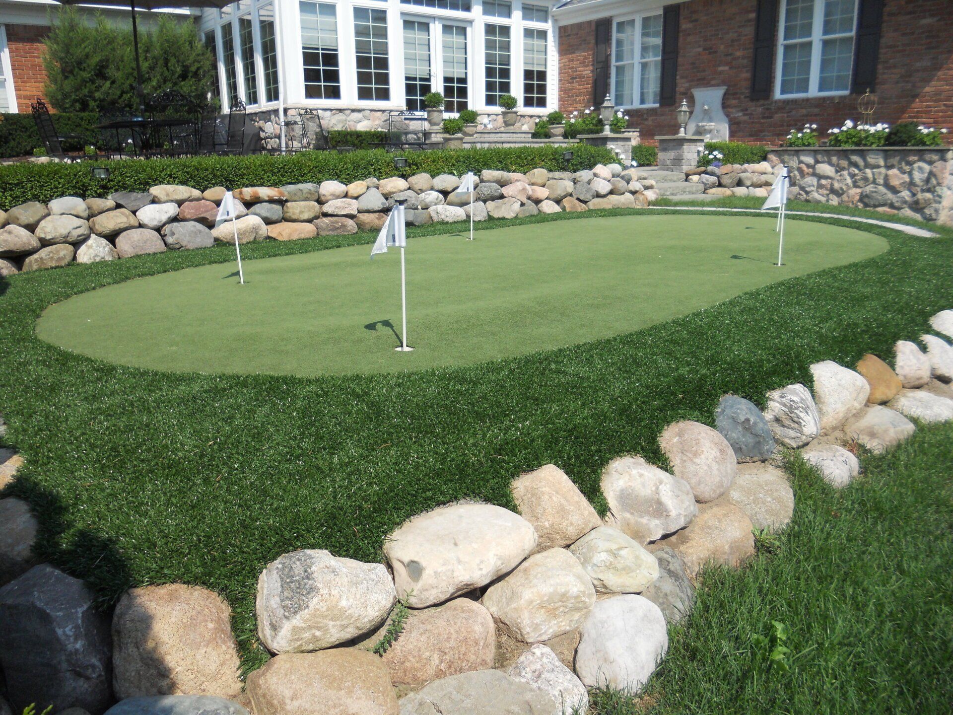A putting green in front of a brick house