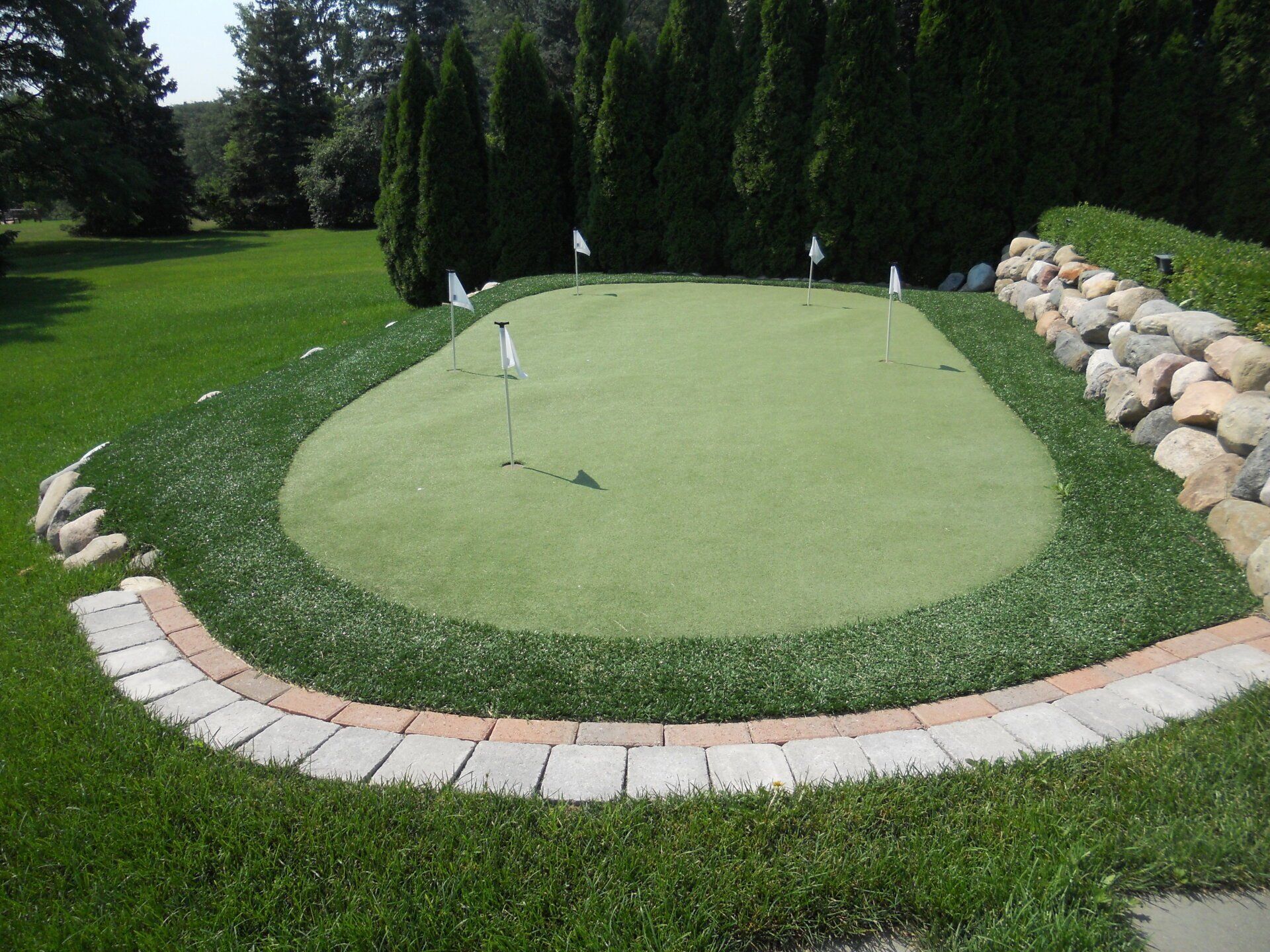 A putting green in a backyard with a brick border